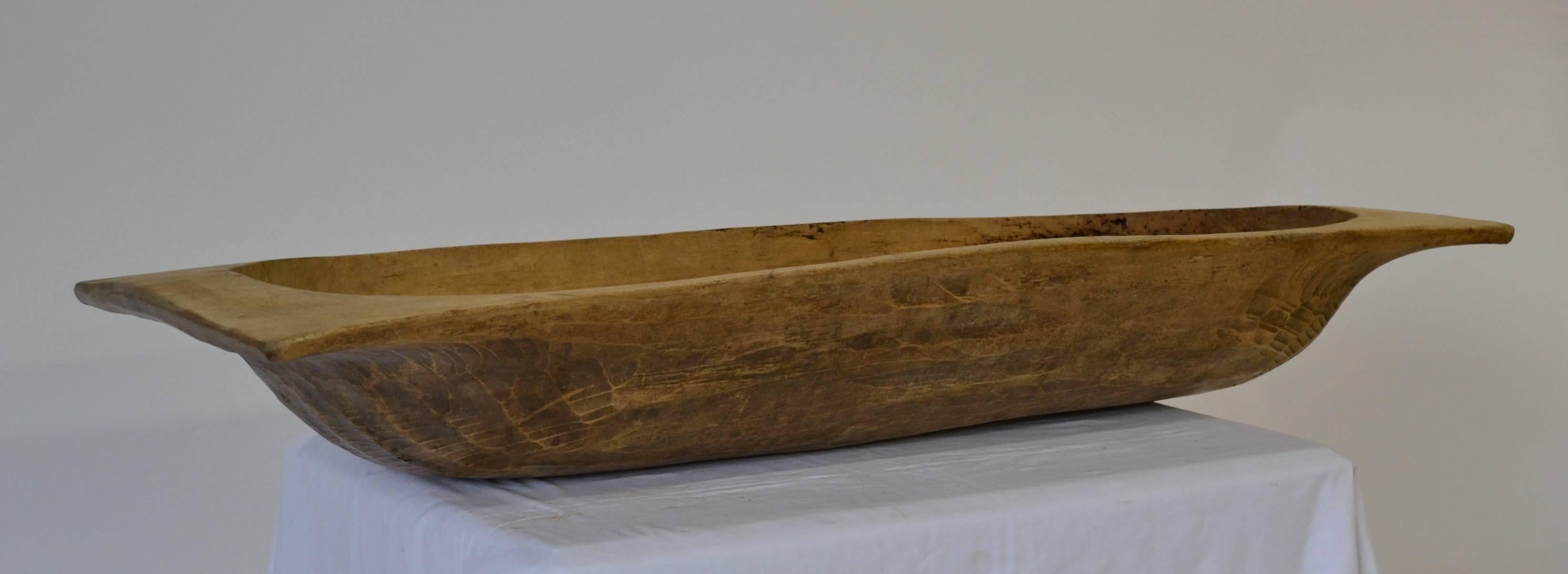 A large attractive antique dough bowl or trog, hand-carved from a split log.  Great as a centerpiece or as a catch-all by the door to toss in scarves and gloves, or use for keeping kindling, logs, or magazines by the fire.
This one has a lovely