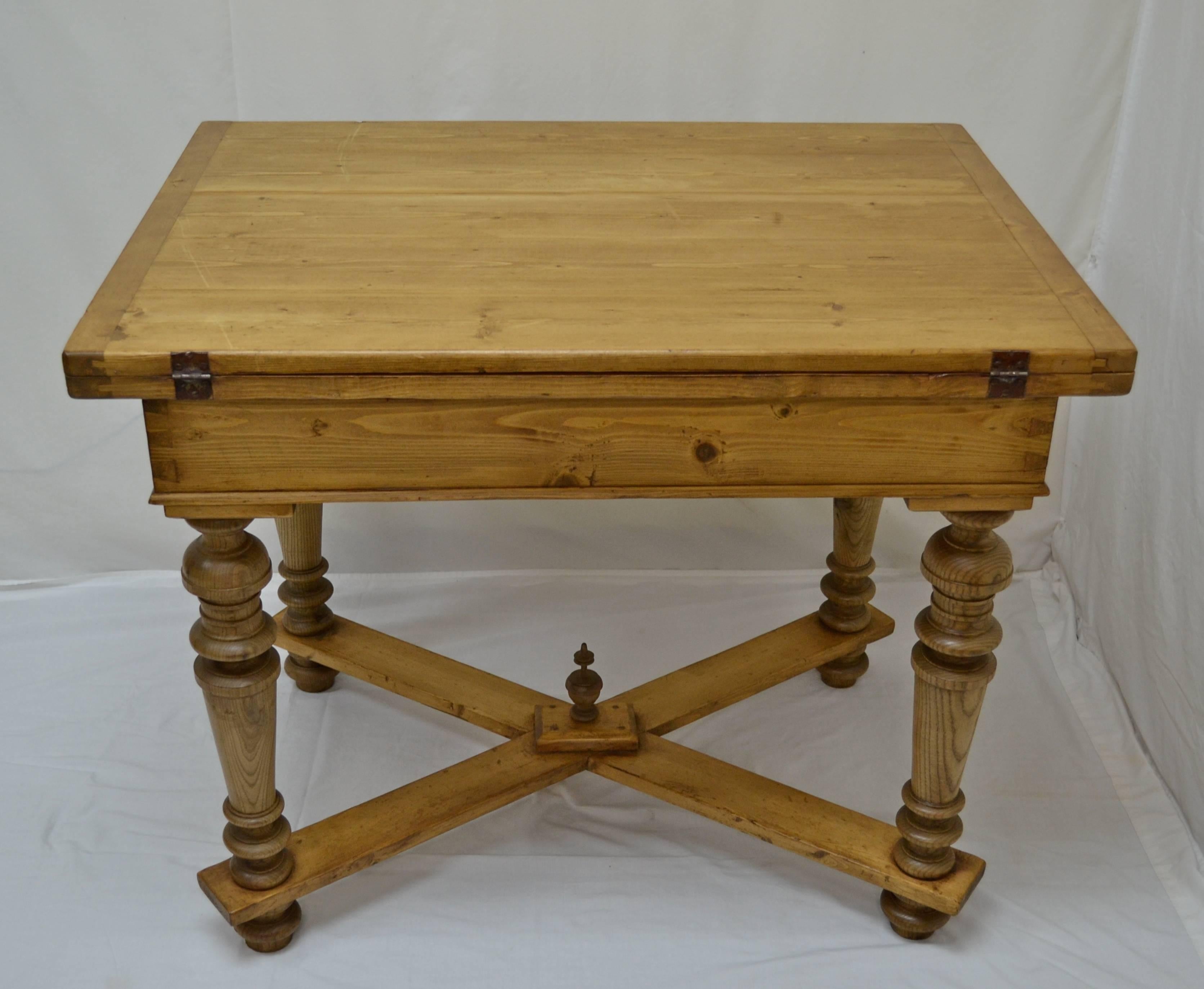 An outstanding pine swivel-top table with elaborately turned pitch pine legs joined by a cross stretcher with a turned hardwood finial at the intersection. Pivot the top through 90 degrees to reveal a deep storage well beneath. Open it on the