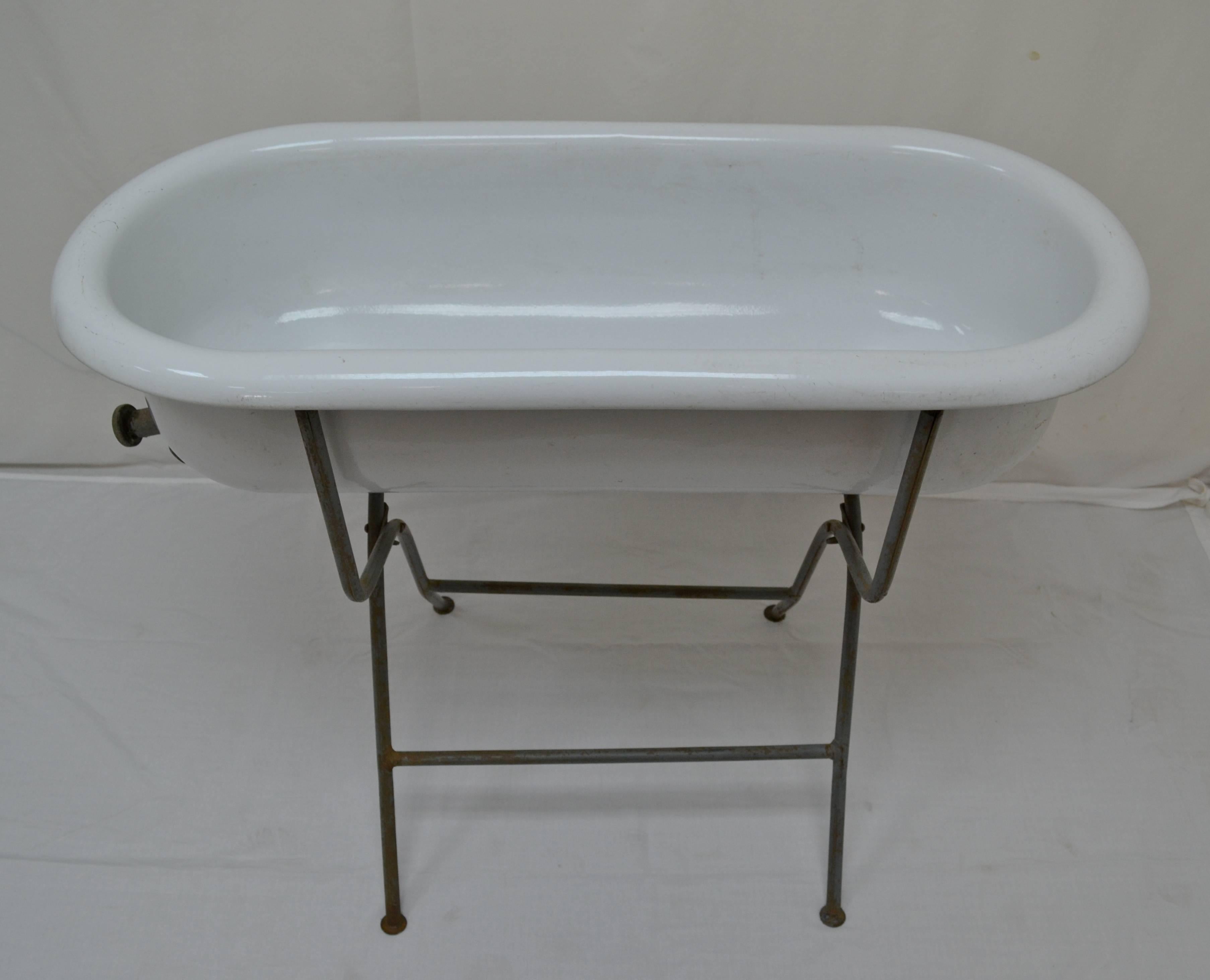 This is a charming vintage porcelain enameled baby bath by Lampart of Hungary, with a working zinc drain tap and mounted on an original folding wrought iron Stand. With summer approaching it would be great filled with bottles of beer or wine on ice,