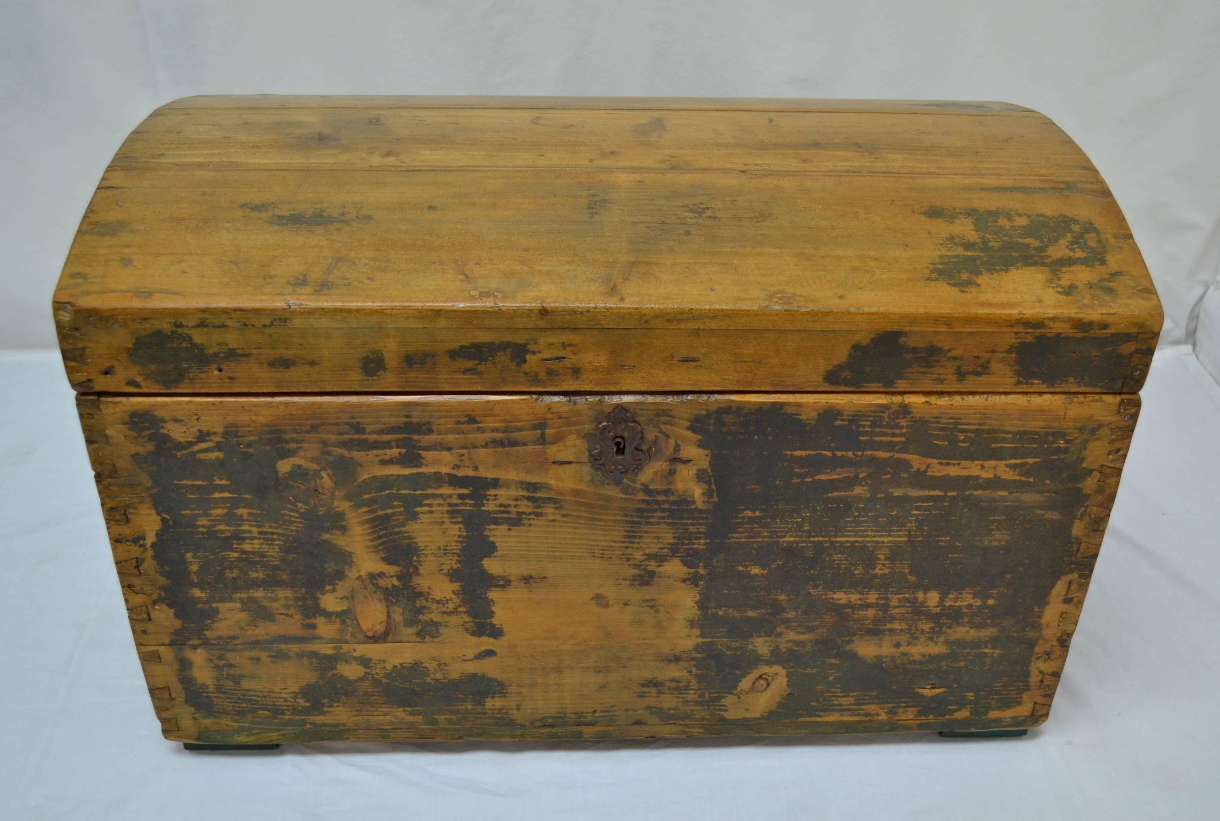 This is a sturdy little dome top trunk with exposed hand-cut dovetails on all corners, a pressed tin Baroque-style escutcheon, and massive iron carrying handles. The top lifts on original butt hinges to reveal a deep storage well inside. The trunk
