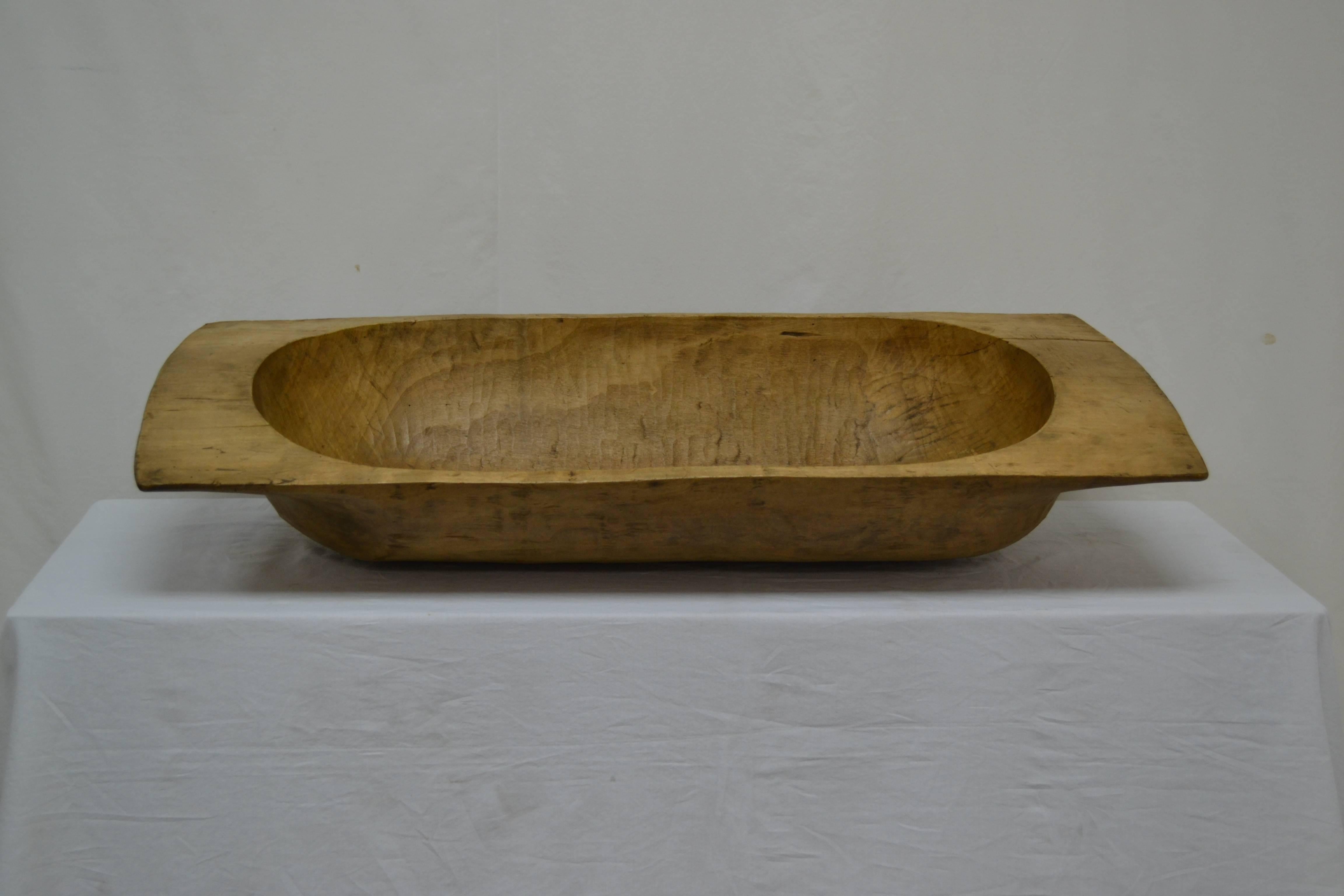 An antique wooden dough bowl or trog, hand-carved from a split log.  This is a beautiful example in a useful size, with one or two superficial cracks.  Great as a centerpiece or as a hallway catch-all.  Use for logs or magazines by the fireside.


