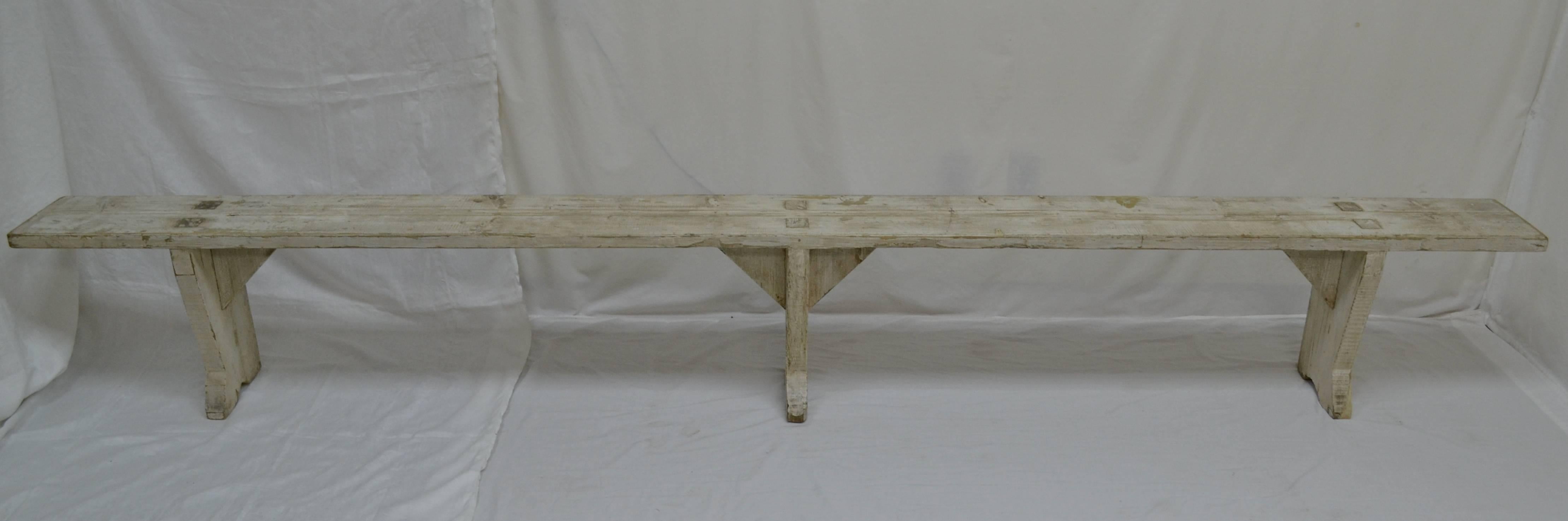 This is a huge form or backless bench over ten feet long. The three trestle-style legs, from stock 2” thick, are through-tenoned into the seat for strength and stability, then reinforced underneath with solid triangular braces. The piece is in old