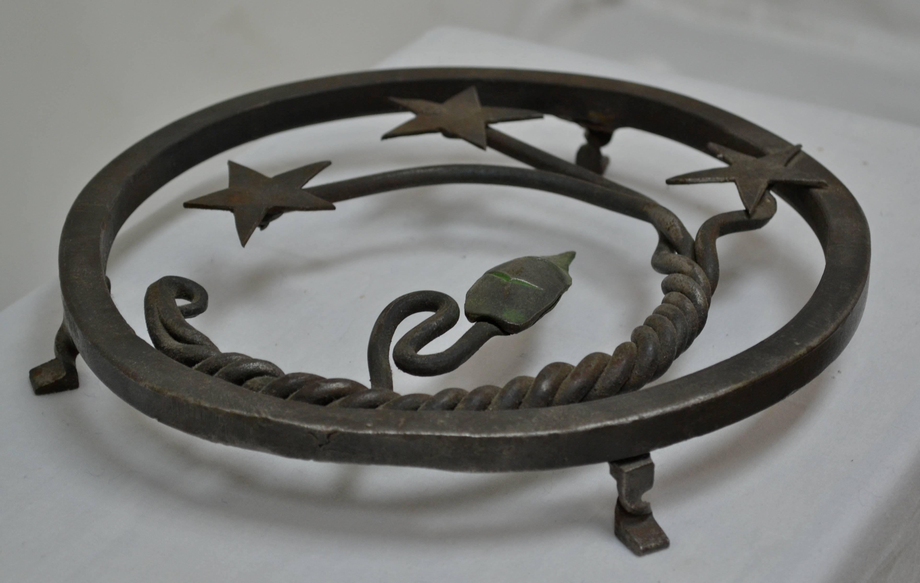 This is a small but beautiful example of the blacksmith's art. This hand-forged iron trivet features a three strand rope twist with stars, and a leaf with a hint of green, within a 0.5