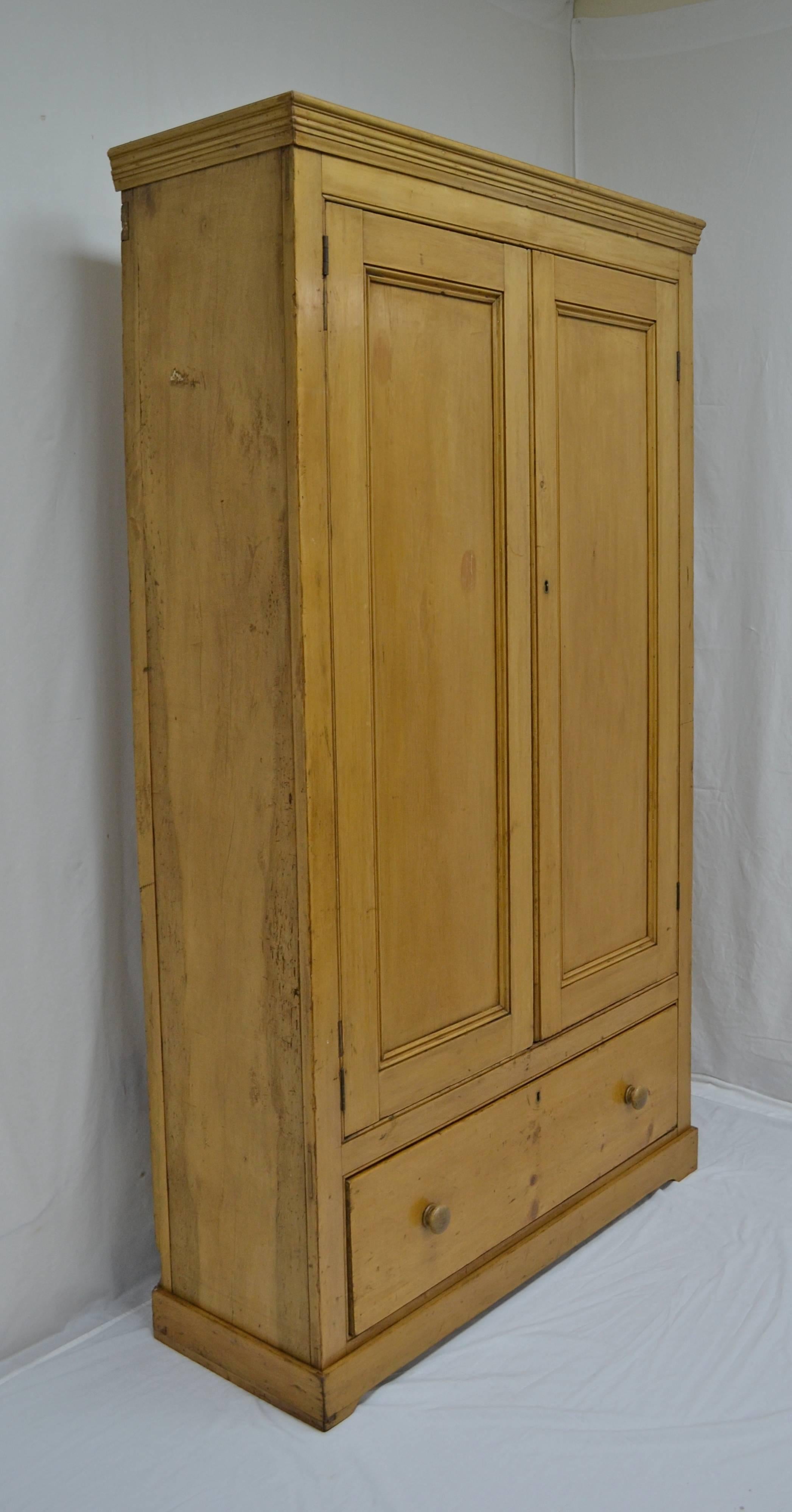 This charming little wardrobe is about as plain and simple and well-made as a piece of English Victorian pine furniture can be. Beneath a tidy crown molding are two paneled doors and one deep, delicately dovetailed drawer with original oak knobs.