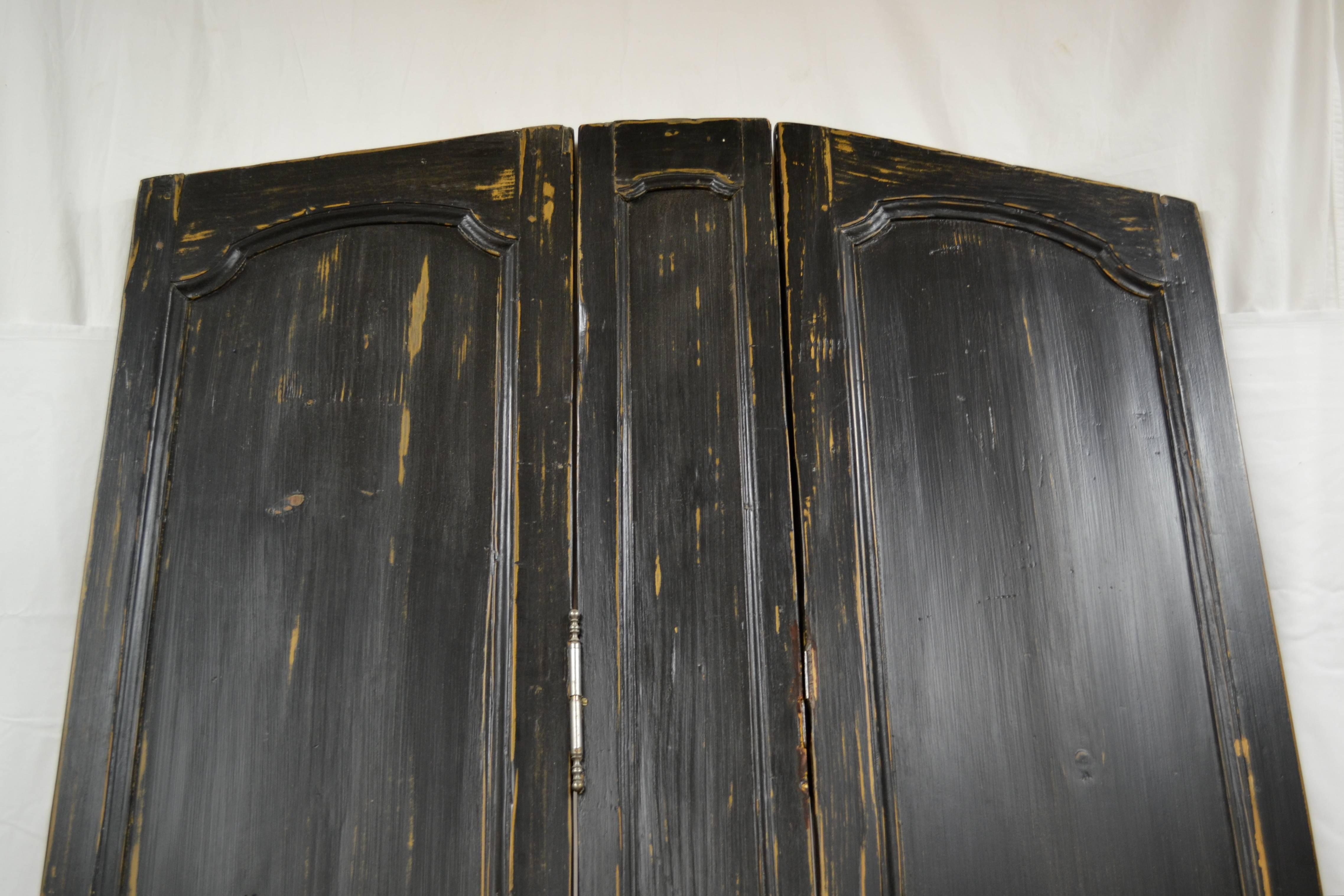 Three mid-19th century French Louis XV style pine wall panels have been joined with steel fiche hinges to form this arched-top folding screen. A central strip, 7.5” wide, stands between two 16” wide panels, one folding forwards, one folding back.