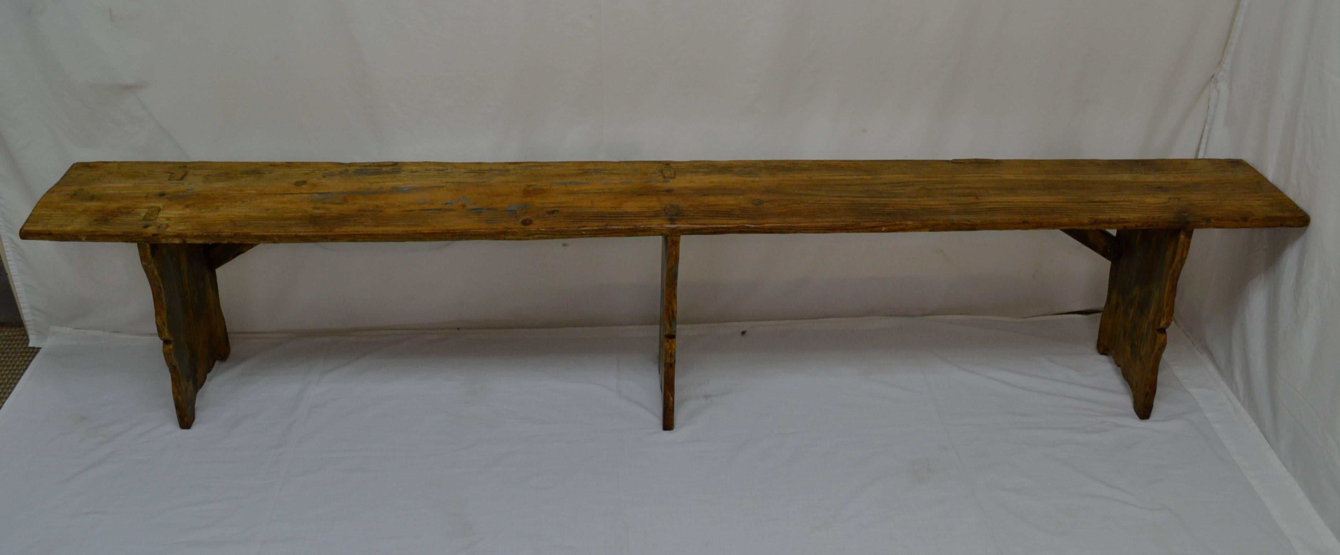 This is a beautiful long pine three-legged backless bench or form. All three trestle-style legs are through-tenoned into the thick single board seat, the outside two being slightly splayed and reinforced with diagonal braces at the back The legs