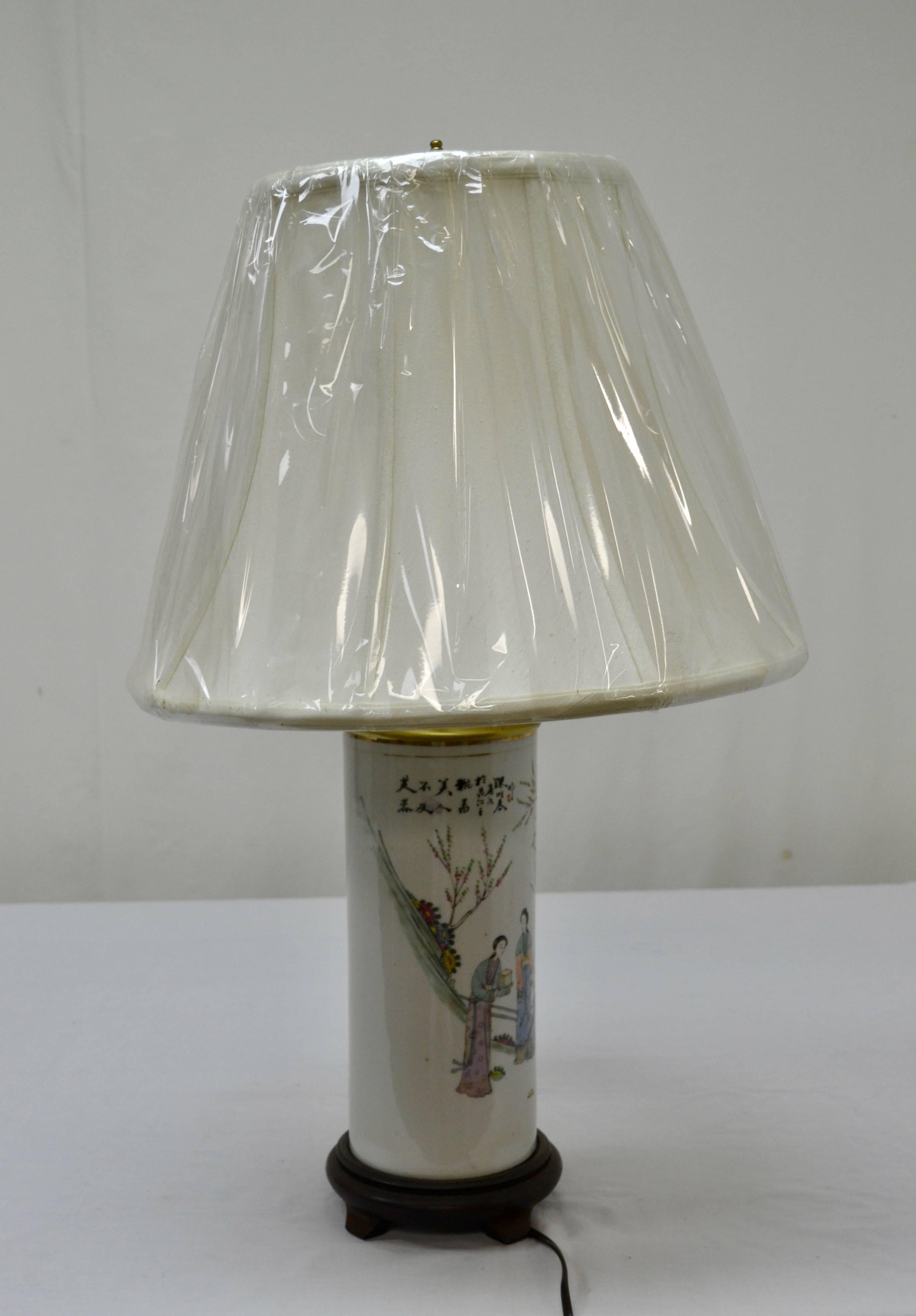 This is a colourful antique Chinese porcelain hat stand, depicting a group of women in a traditional Chinese setting, converted into an elegant table lamp with a fine linen shade and mounted on a footed hardwood base. Shade dimensions 16
