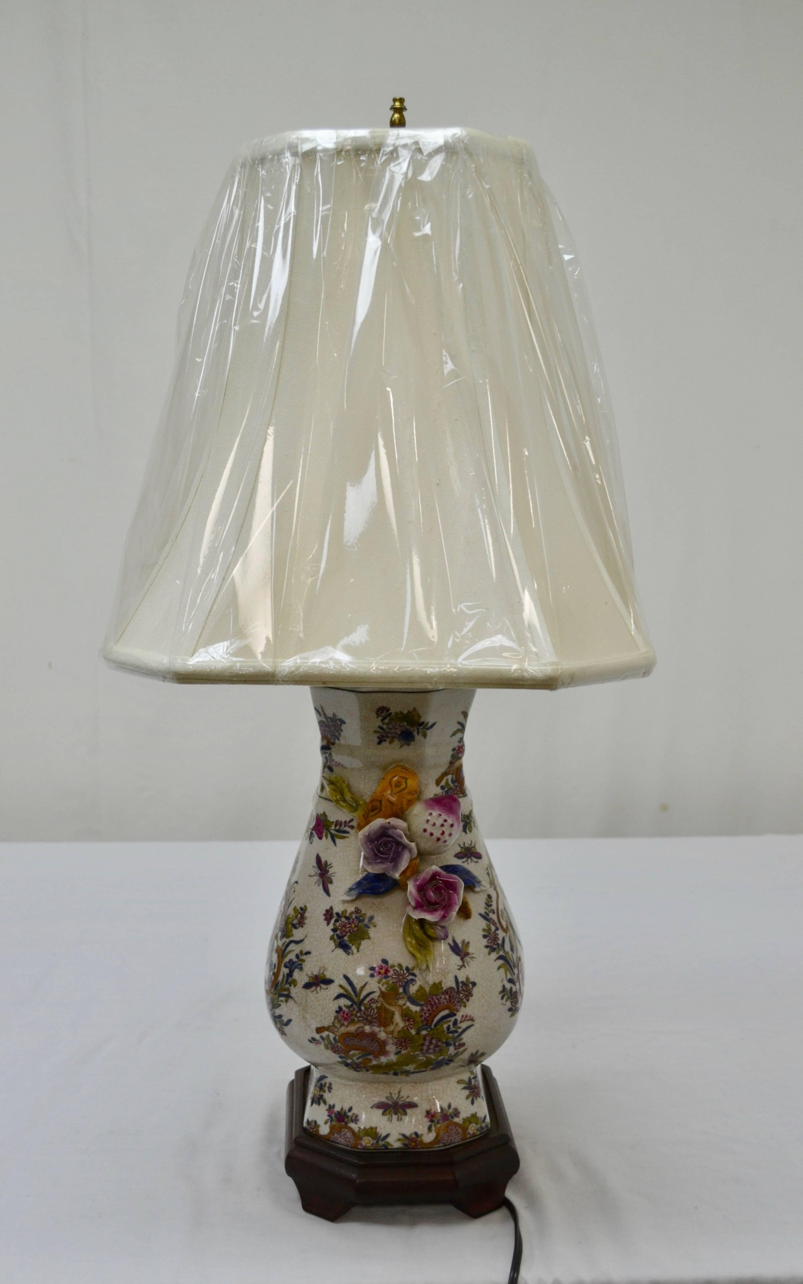 Se trata de una reproducción de un jarrón de porcelana china, elaboradamente decorado con una representación de querubines en un colorido ambiente rococó, convertido en una elegante lámpara de mesa con una fina pantalla de lino y montado sobre una