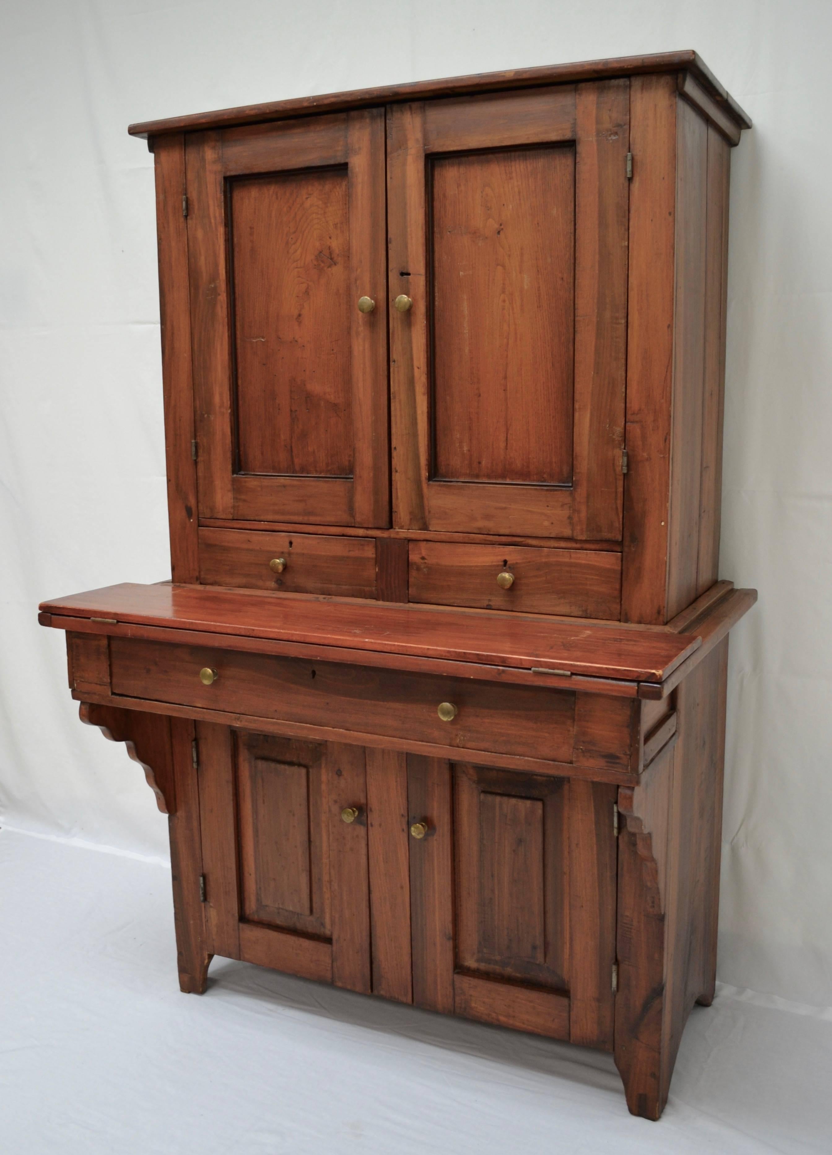 This is a charming and versatile plantation desk, journeyman-made in two pieces, in walnut and poplar. In the upper section two paneled and through-tenoned doors open wide to reveal seven small drawers and a number of vertical and horizontal