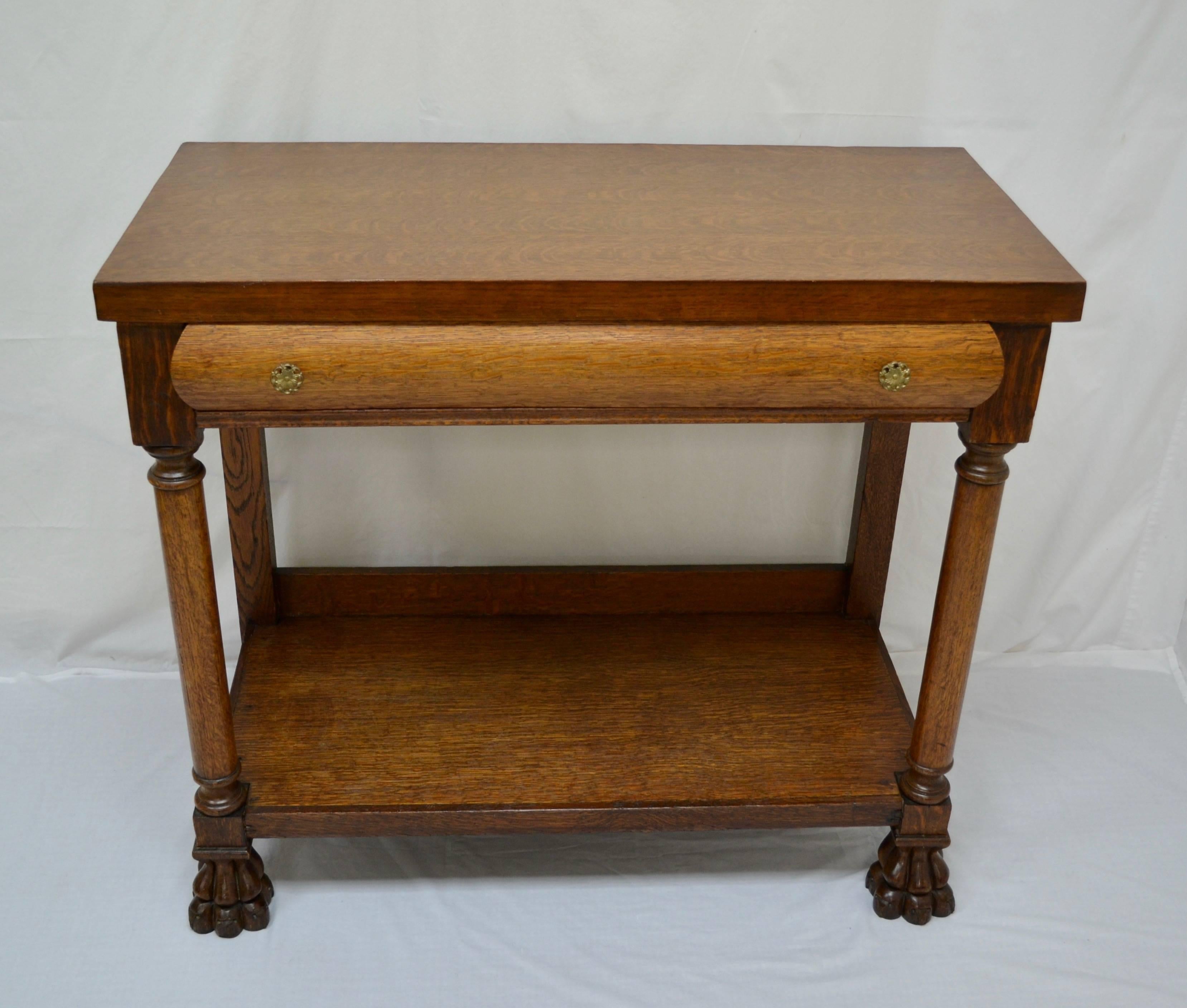 This turn of the century oak pier table has handsome lines and a distinguished presence. The quarter-sawn top has a beautiful grain pattern and is banded to simulate a thickness of close to 2”, as is the potboard shelf beneath. The two front legs