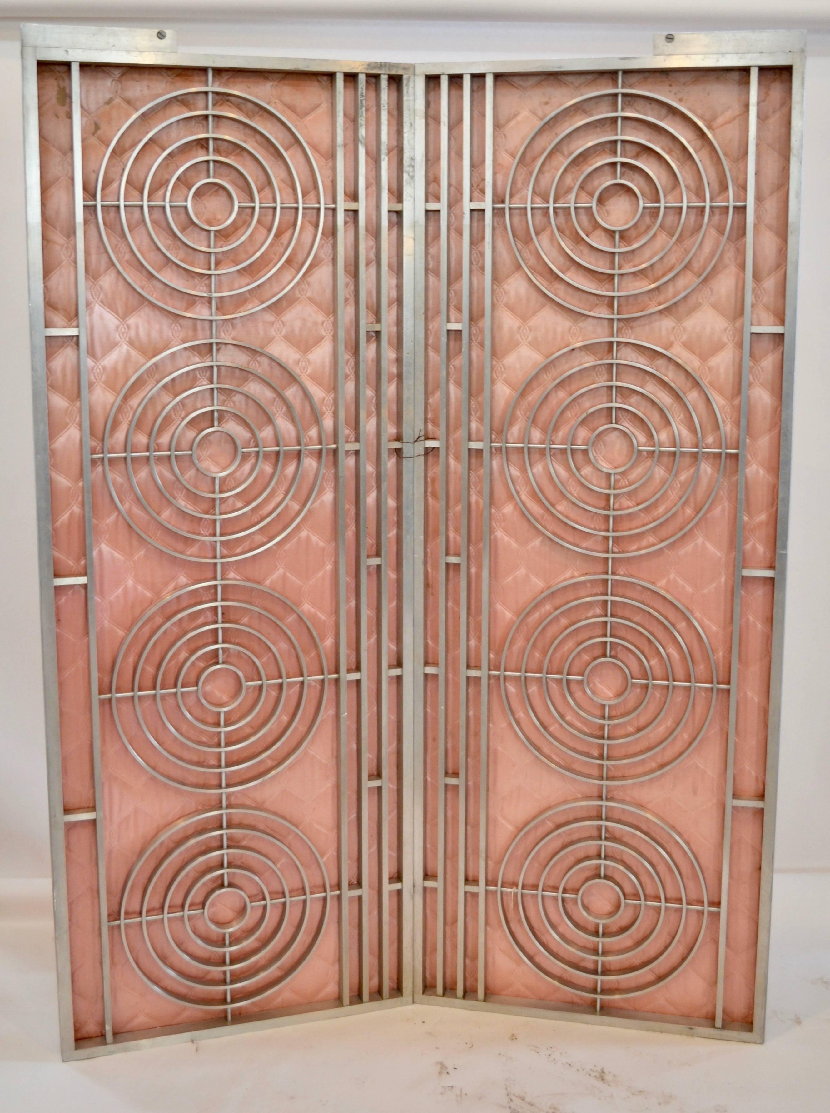 Pair of moderne interior gates with pink paneled upholstery sourced from the textile baron Henry Magee residence in Bloomberg, PA. Each gate features four concentric five ring ornaments in brushed over brass.
