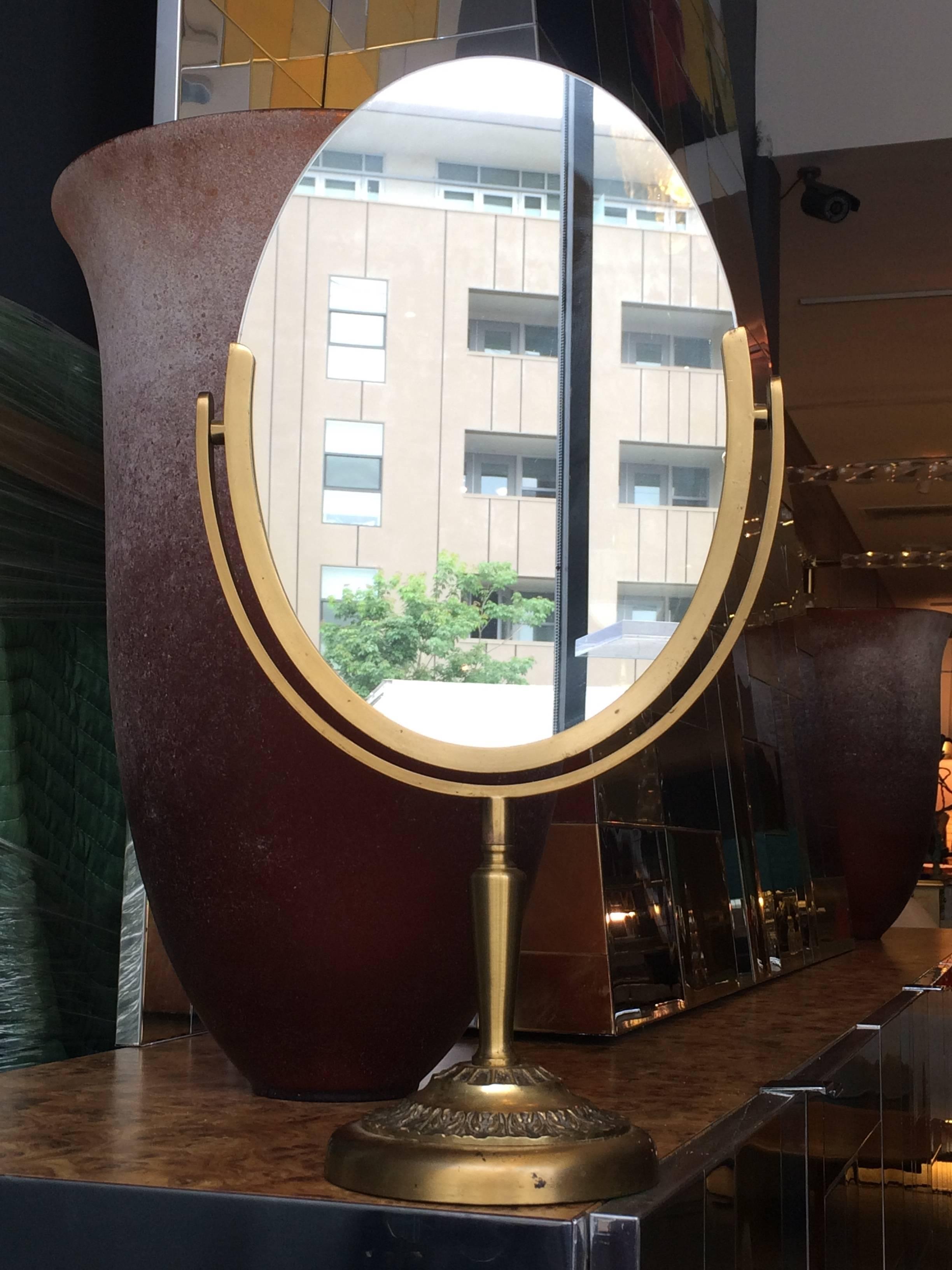 Magnifique miroir ovale conçu et fabriqué par Charles Hollis Jones dans les années 1960. Le cadre et la base du miroir sont en laiton antique. Le miroir est double face et peut être retourné pour être utilisé des deux côtés.
L'œuvre est signée par