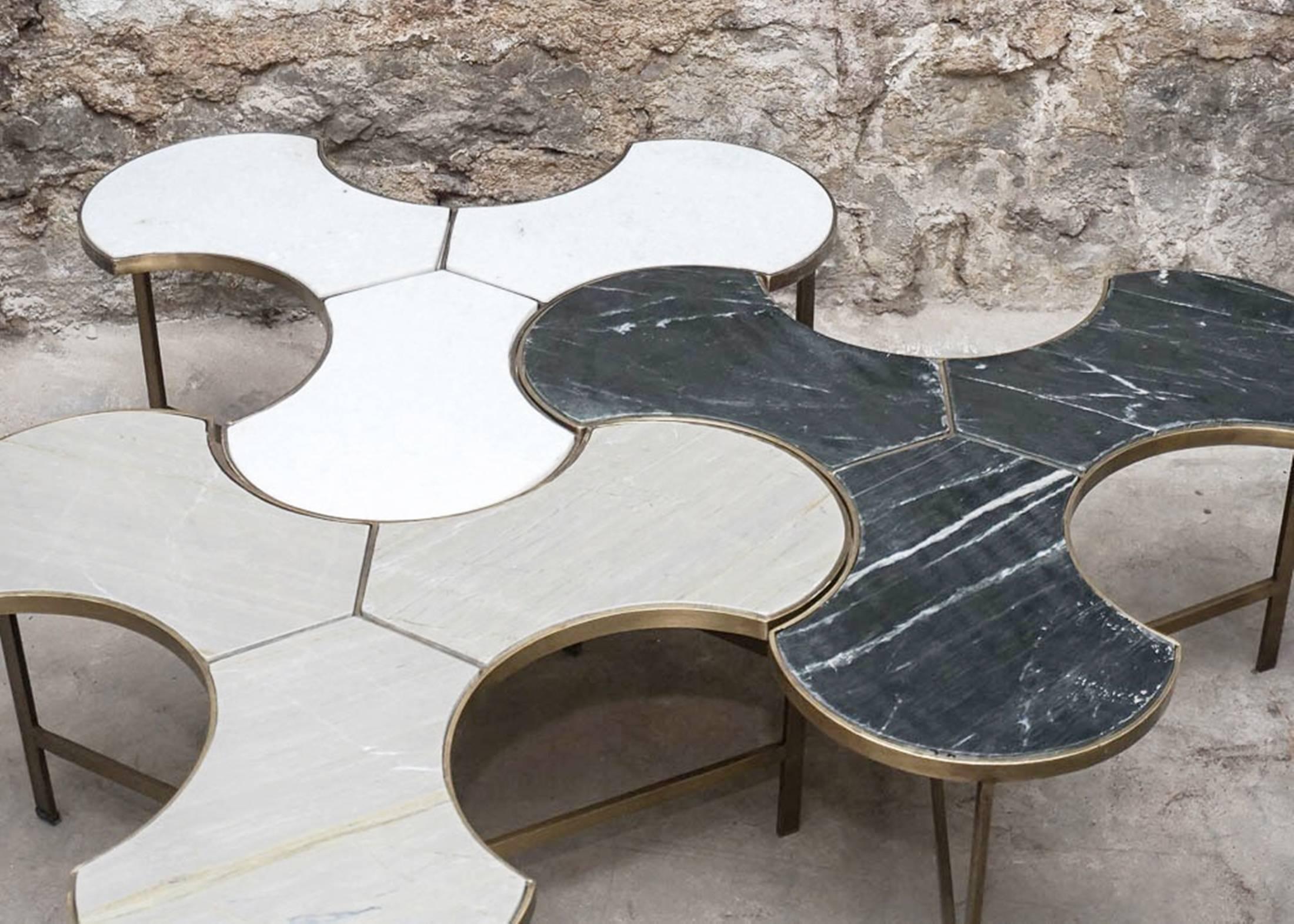 A trio of marble and brass coffee table. These trefoil puzzle pieces have removable marble inset tops and they fit together to create a beautiful coffee table one each of white, grey, and black with brass frames and block with a Y stretcher. The