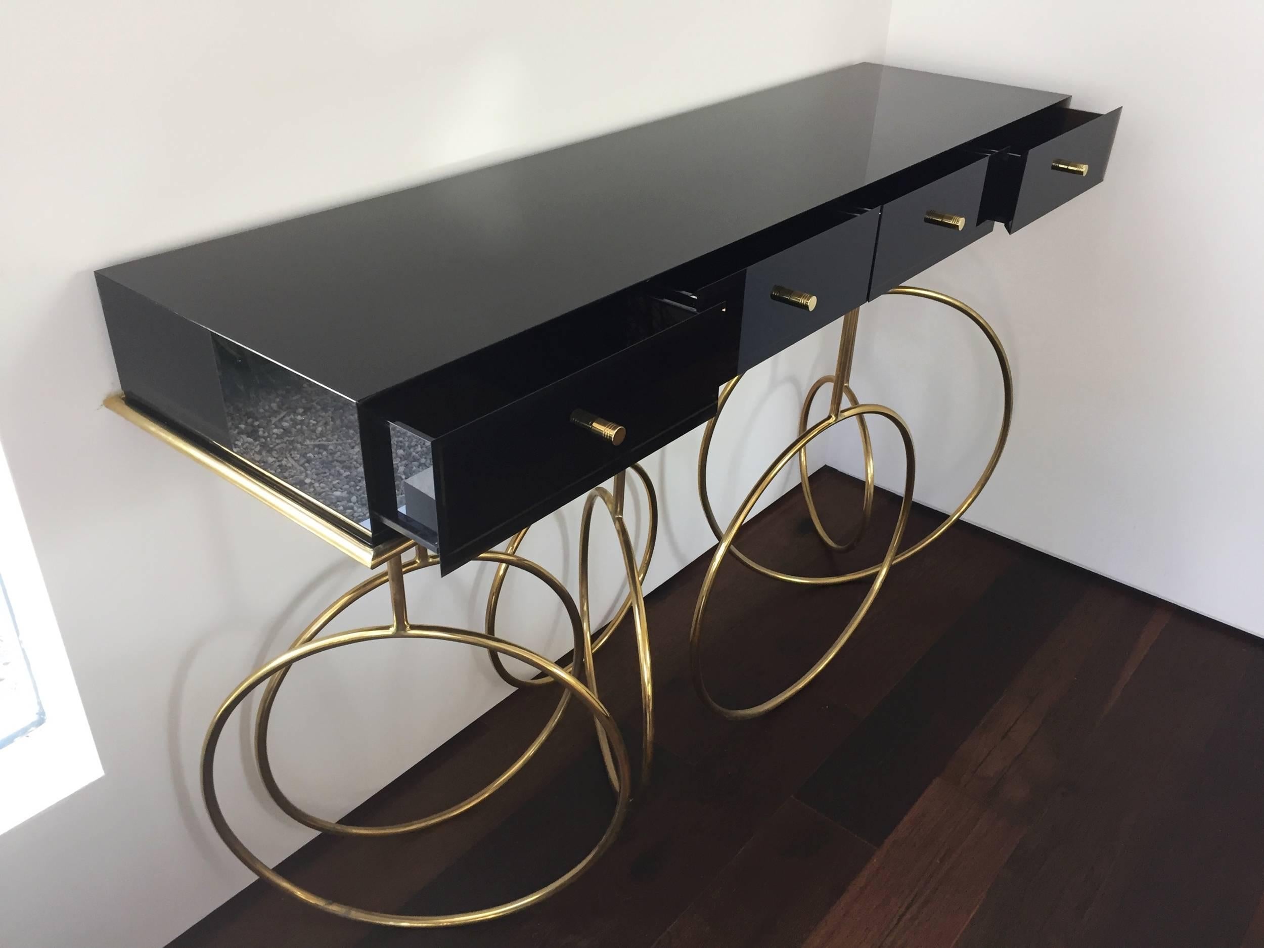 Stunning console table designed by Amparo Calderon Tapia for Cain Modern.
The table is executed in bronzed Lucite and solid brass base, having four drawers making it ideal to use as a console table or even a desk.

The brass base needs to be