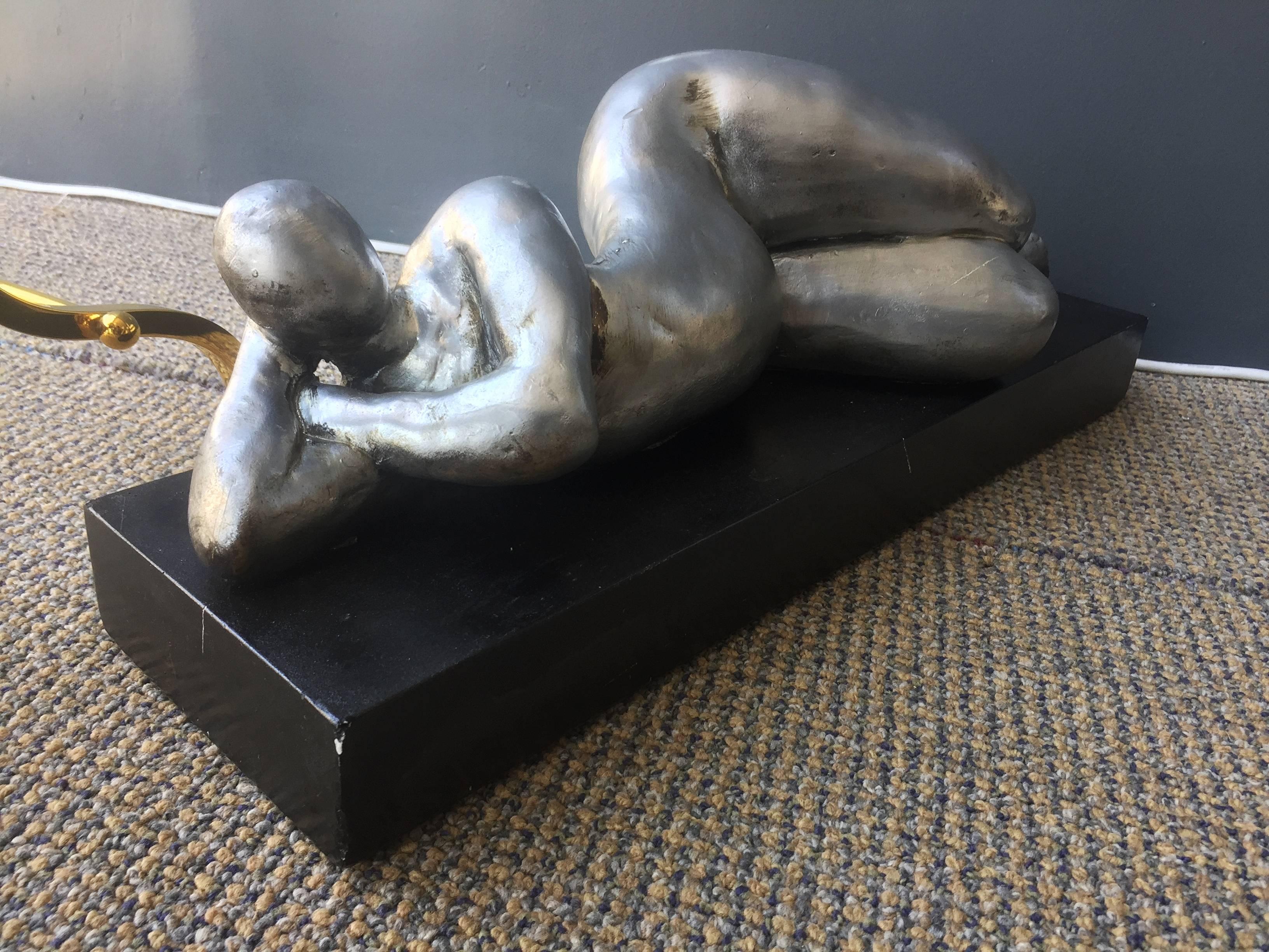 A cast stone sculpture of a human form by Attila Tivadar, from Attila’s Bay shore Art Studio in San Francisco. This piece depicts a female figure with exaggerated curves lying on the side with one arm resting over the chest and the other resting
