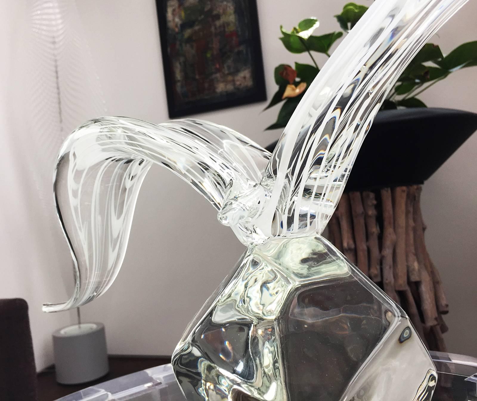 A Licio Zanetti Murano bird sculpture. This sculpture depicts a bird with outstretched, curved wings with white lines running through it perched atop a geometric shaped bottom. The base of this sculpture is hand signed.
Measurements:
24.0