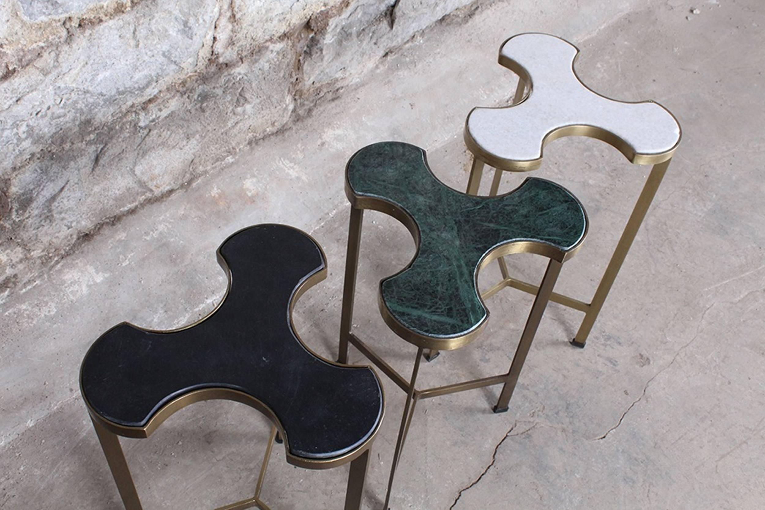 A trio of marble and brass end tables. These trefoil puzzle pieces have removable marble inset tops— one each of white, grey, and black— with brass frames and block with a Y stretcher. The pieces fit together or stand separately.

Dimensions: