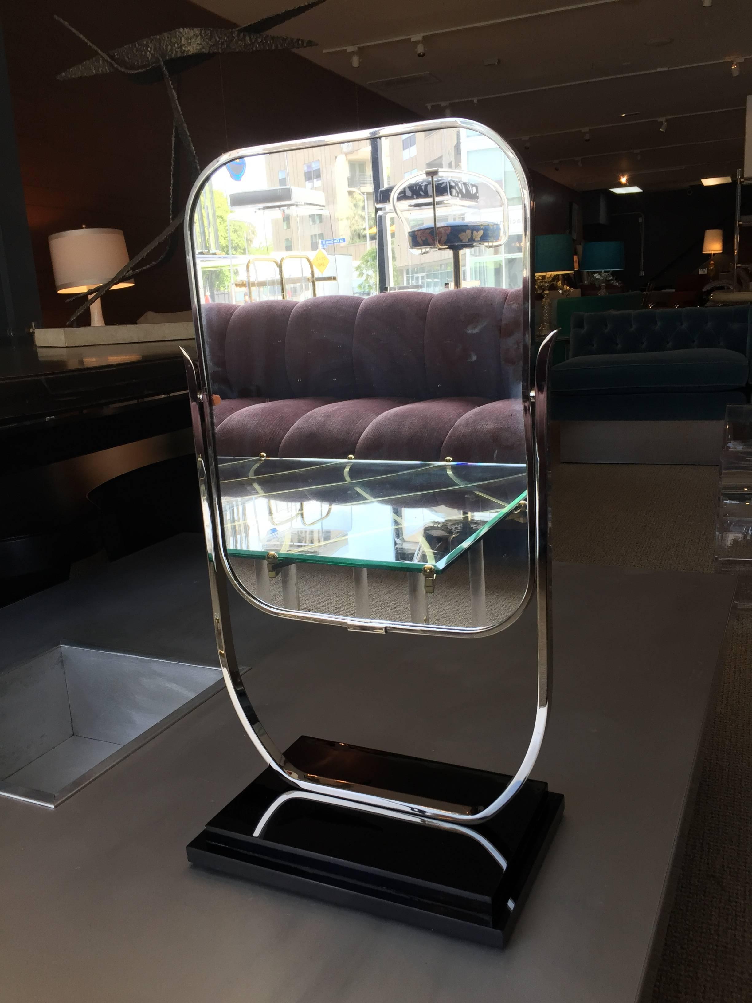 Beautiful deco style vanity mirror dating from the early 1950s, dual sided mirror with a black Lucite pedestal base and a tilting feature to better catch the light.

The metal is polished nickel and it was recently re-plated, the mirror was