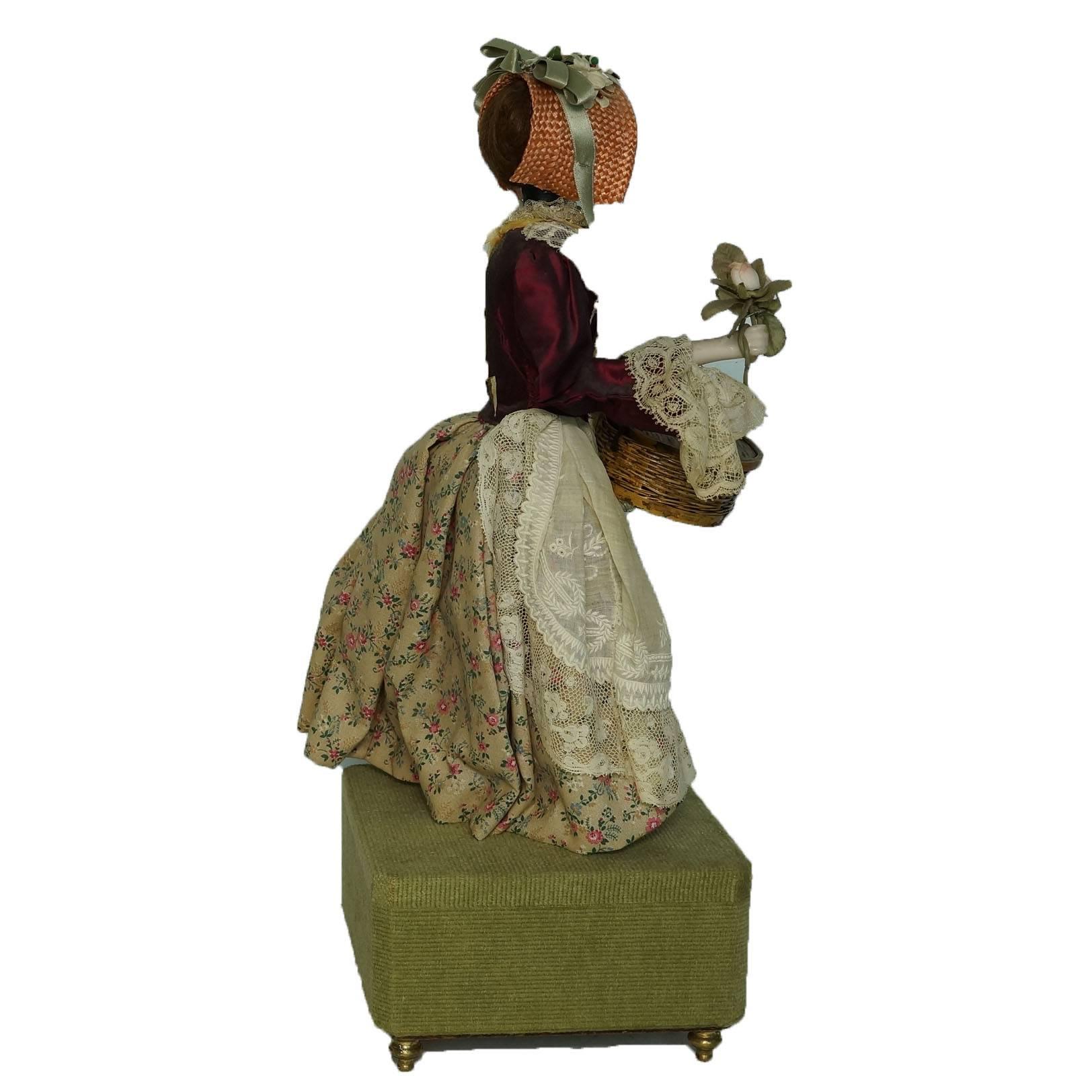 Automaton figure of a standing girl holding flowers playing music.
The music does not work so well.