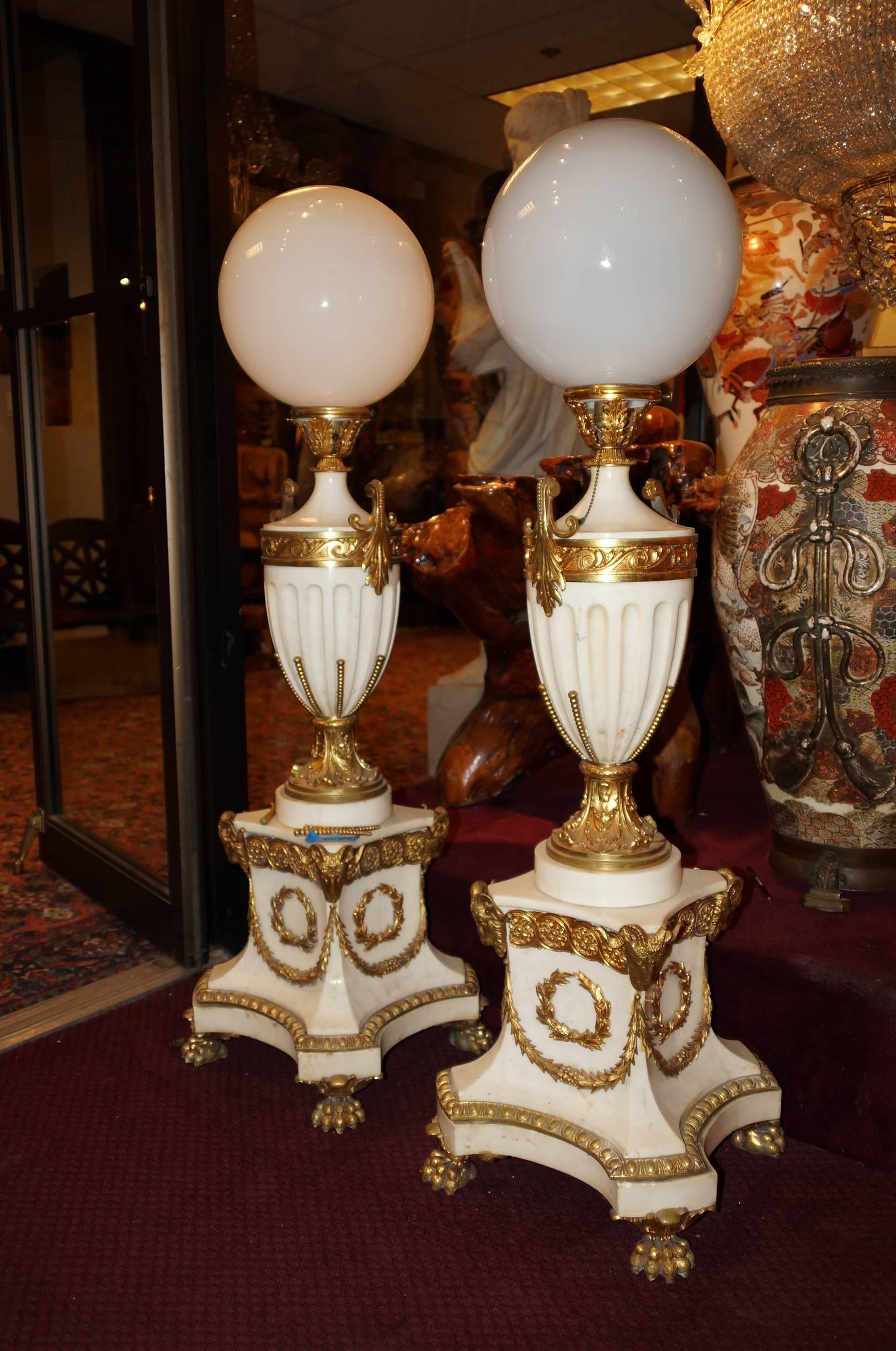 Pair of French Louis XVI style white marble and bronze floor lamp torchieres with rams head and paw feet.
Stock Number: LL38