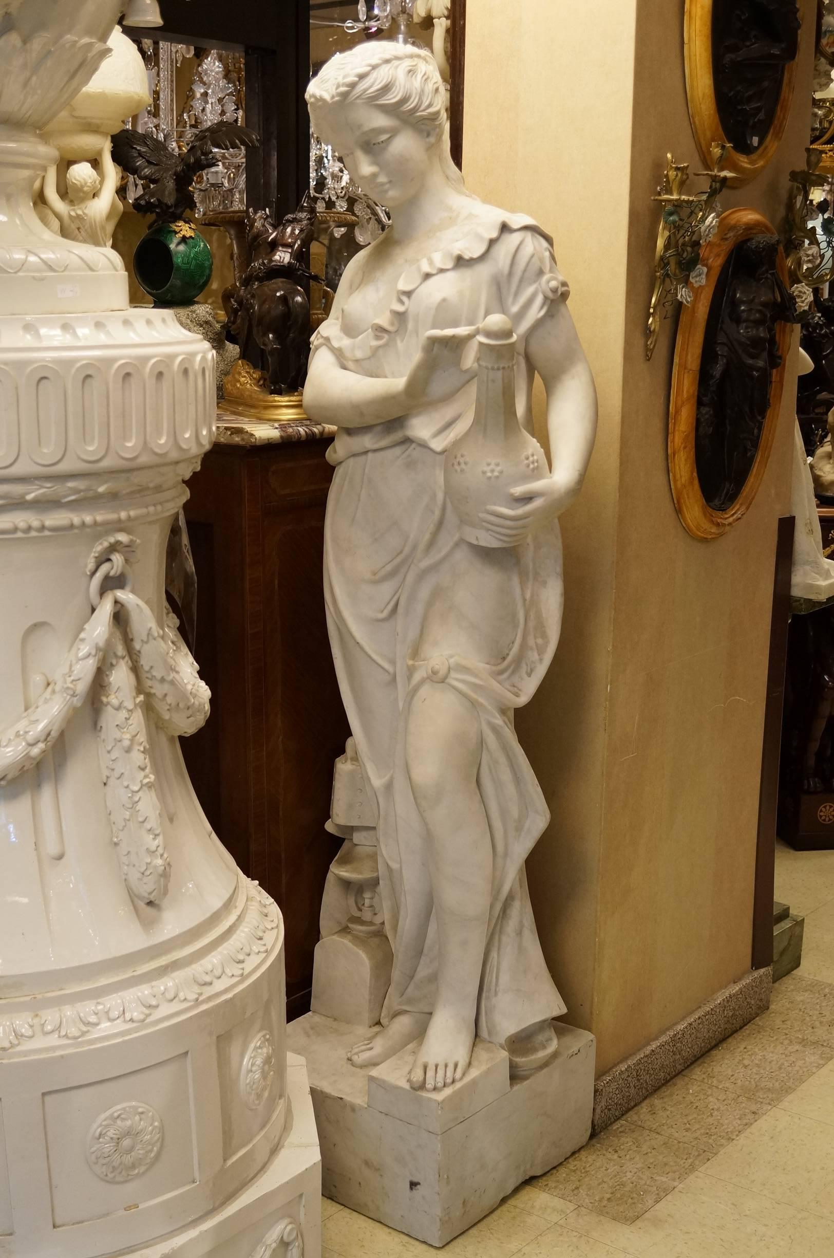 A very large and finely carved Italian marble statue of a neoclassical semi-nude beauty holding a wine jug.
