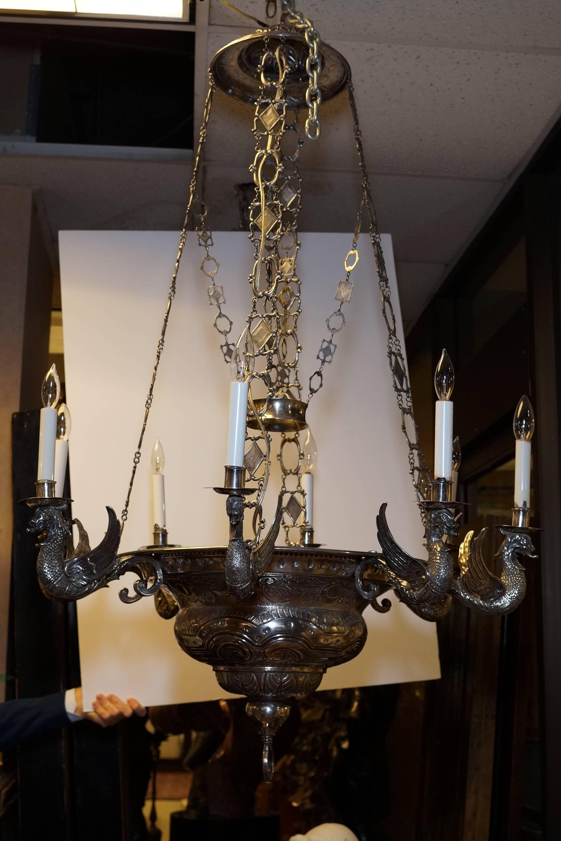 A large silver eight-light chandelier, probably South American,
in Baroque style, the deep bowl with eight winged demilune sconces, with canopy and four chains, wired for electricity
apparently unmarked

317 oz 10 dwt gross
9877 g.