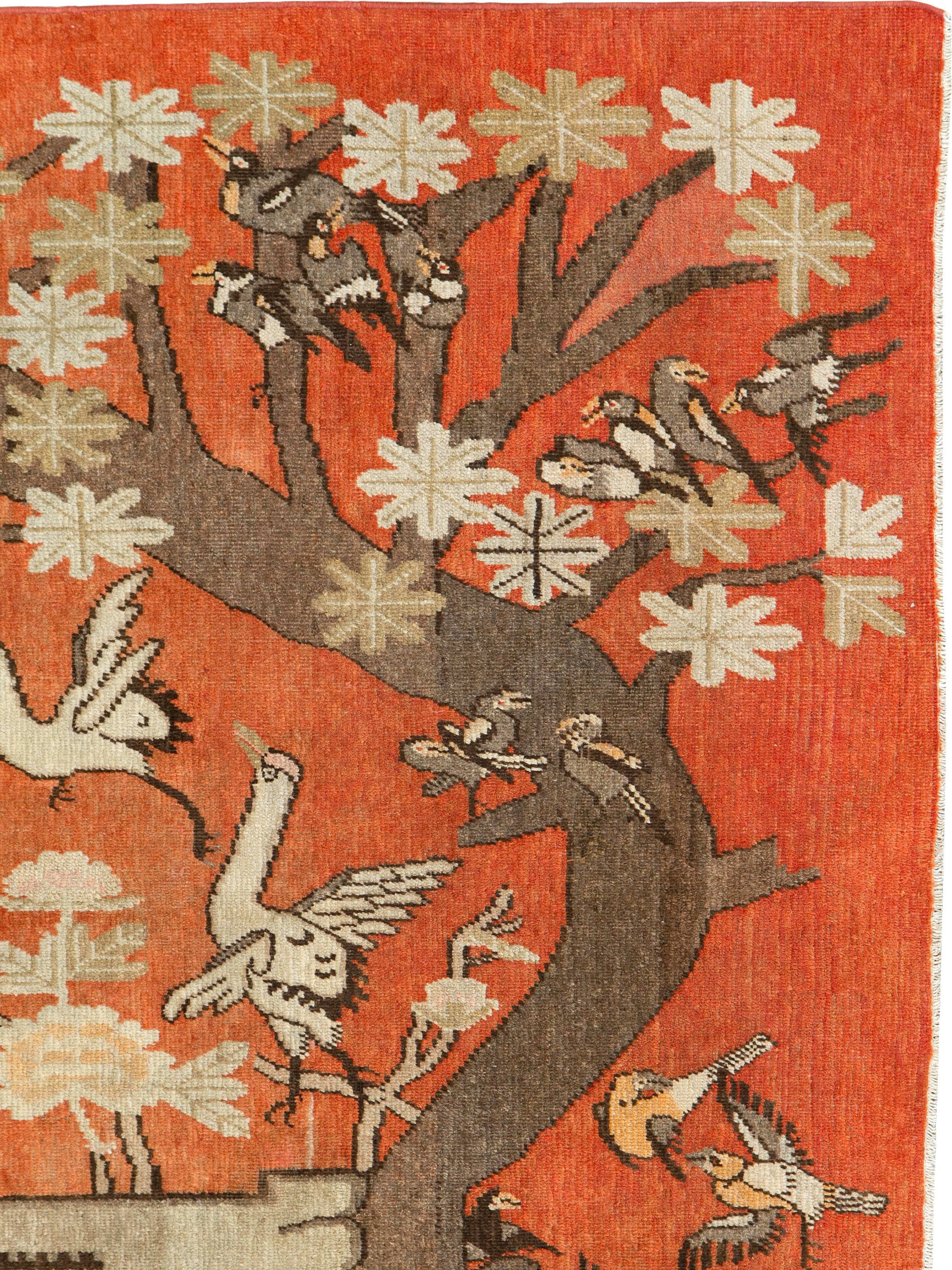 An antique East Turkestan Khotan rug from the second quarter of the 20th century. The pictorial design shows several species of birds flocking around one large tree.