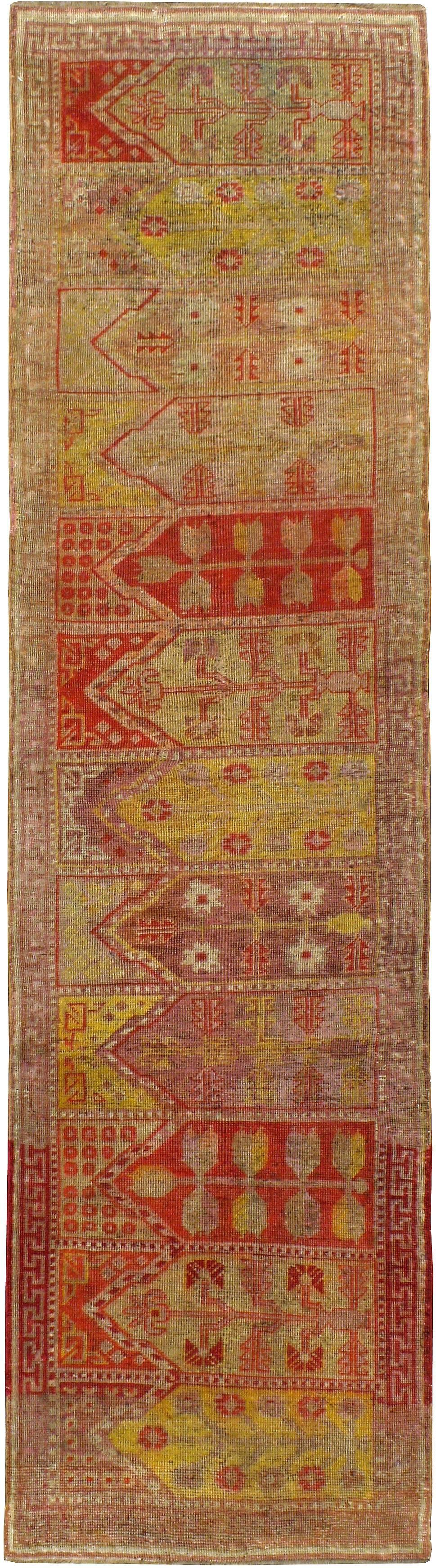 An antique East Turkestan Saf (also spelled Saff or Saph) Khotan rug from the first quarter of the 20th century. The elements of this runner make for a great ecumenical context. The Mihrab design in each of the 12 niches that compose this rug makes