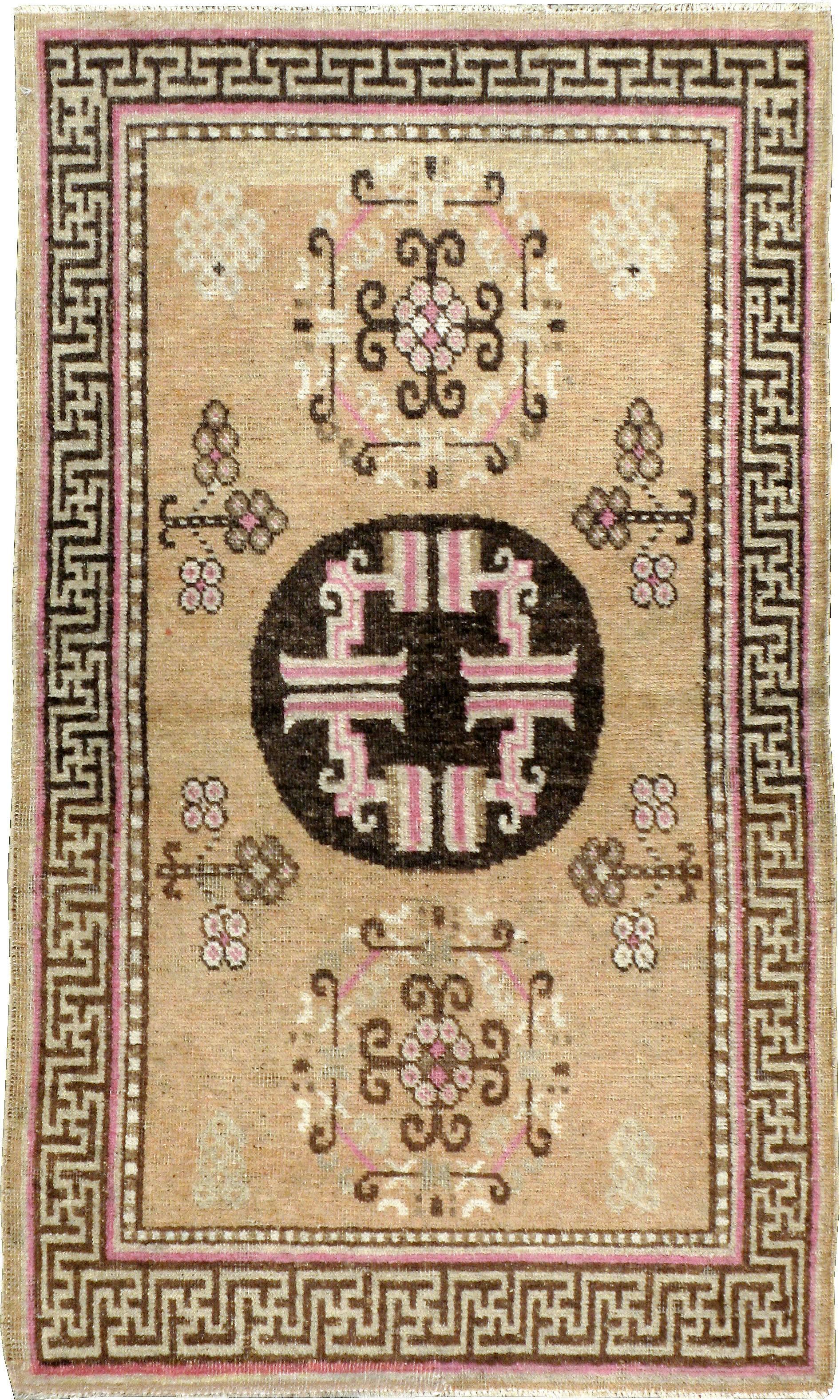 An early, 20th century East Turkestan Khotan carpet with a field made up of three primeval cloud sign medallions and four pomegranate plants. It is surrounded by a T-element Meander border with the ancient symbol of peace in Buddhist, Hindu and