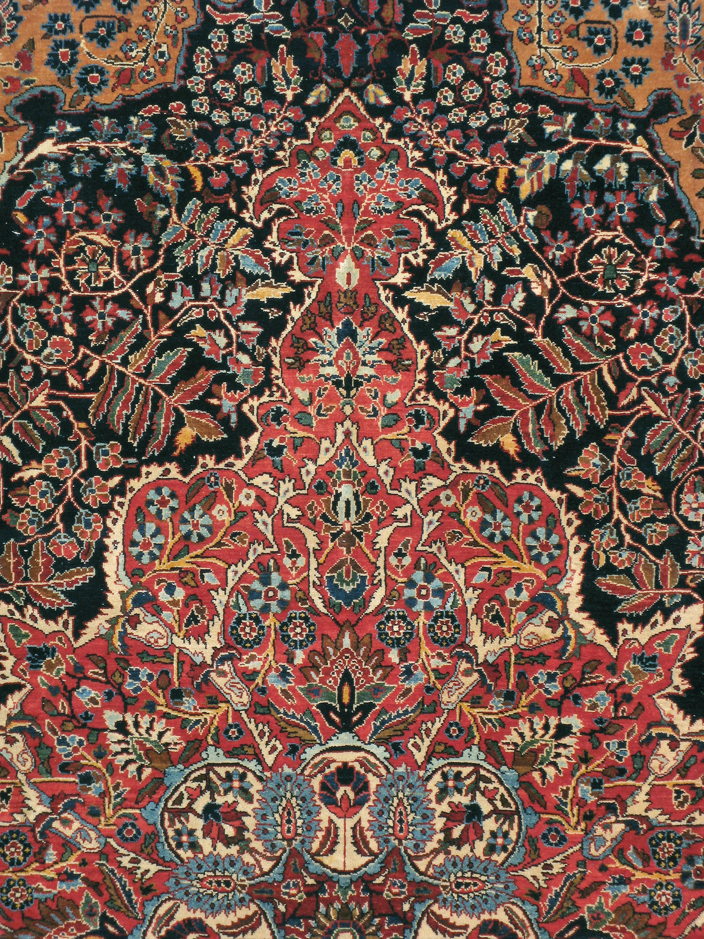 An antique Persian Sarouk carpet from the early 20th century. Even in the “American” style Sarouk period, the Arak province village weavers produced extraordinary medallion carpets and this example is one of them. A very complex red medallion is