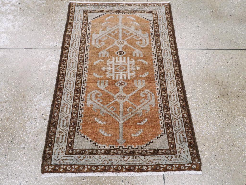 Ein alter persischer Malayer-Teppich. Das gekerbte, rostfarbene Unterfeld zeigt ein zentrales, elfenbeinfarbenes Quadrat mit einem Dreizack, darüber und darunter befinden sich kühne V-förmige Blatt- und Blütenelemente. Die Hauptbordüre aus Perlen
