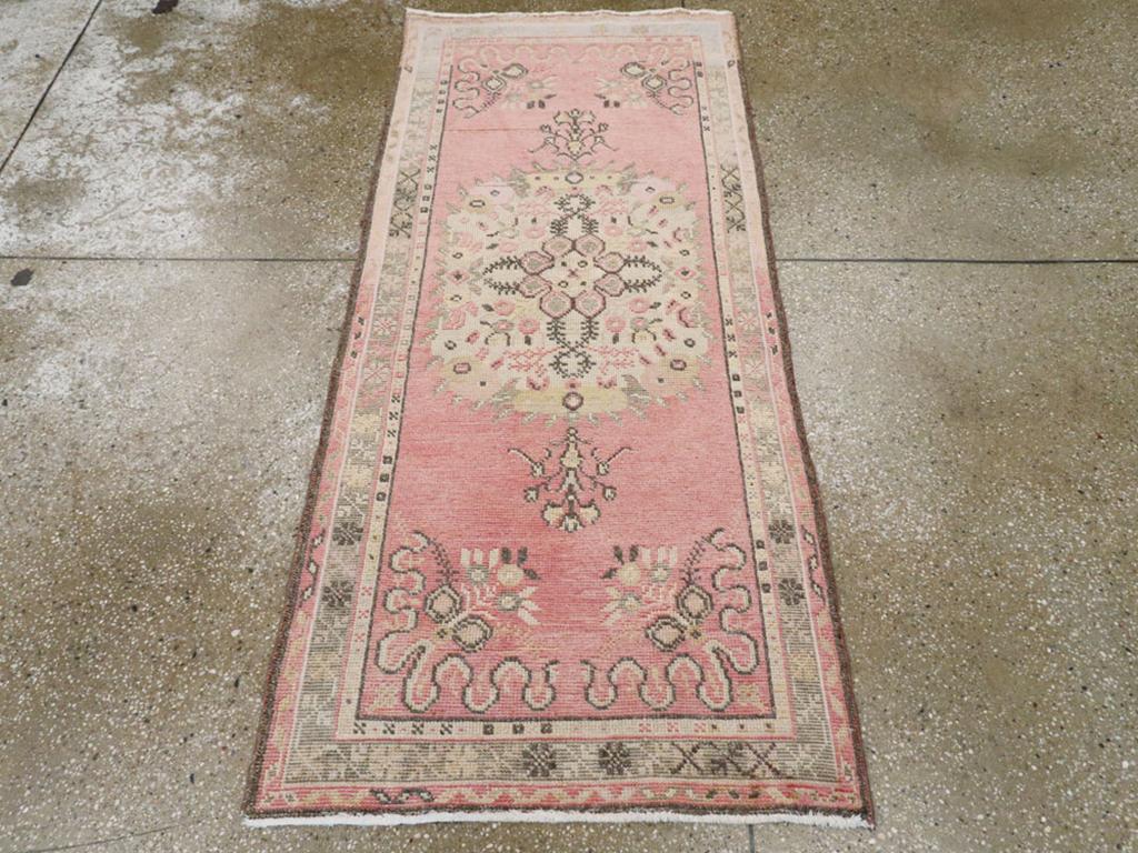 Ein alter türkischer Oushak-Teppich. Das rosafarbene, halboffene Feld zeigt ein Sandmedaillon mit kleinem, stilisiertem Blumendekor. Die Medaillon-Anhänger sind realistisch gezeichnete Blumen im Profil. Die Ecken sind aus Bändern und