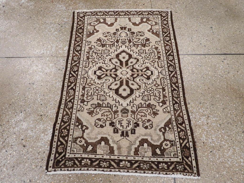 Un tappeto persiano vintage Malayer. Il campo sabbioso è riempito da un medaglione a quattro lobi di colore avorio e marrone scuro e da spruzzi floreali a forma di C. Gli angoli di colore marrone scuro hanno la forma di un quarto di medaglione e il