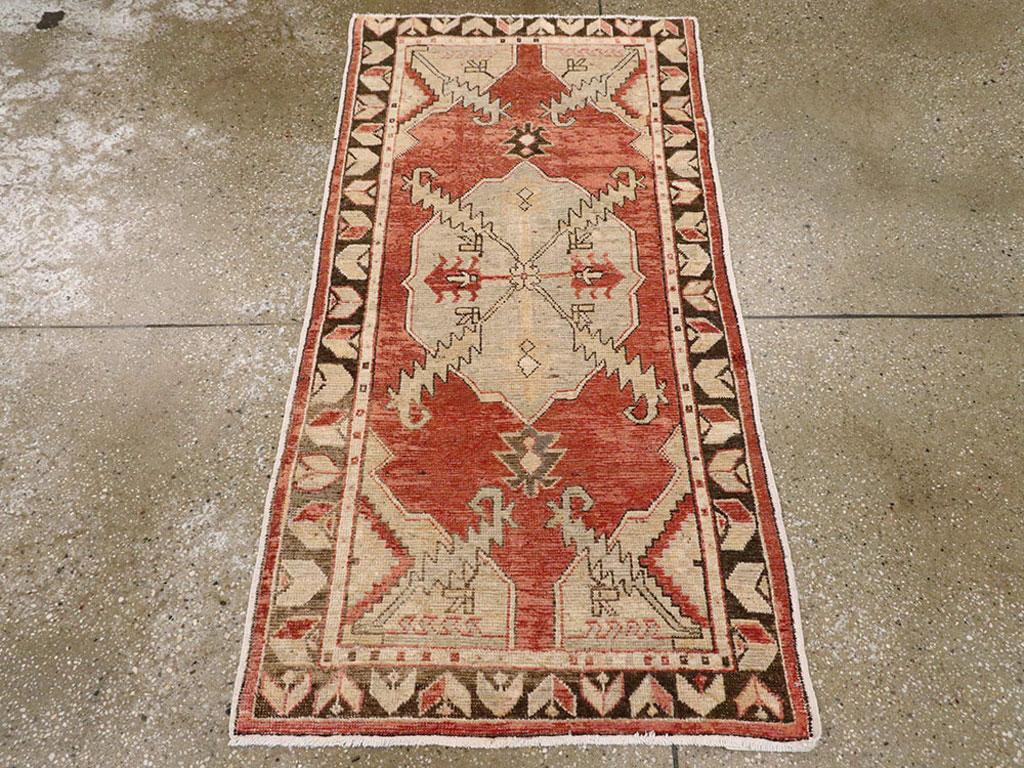 Un tappeto Oushak turco vintage. Vigorose foglie a dente di sega spuntano dal medaglione e dagli angoli nel campo rosso di questo sparpagliamento da villaggio turco. Il bordo marrone abraso presenta motivi di foglie e fiori chevron al