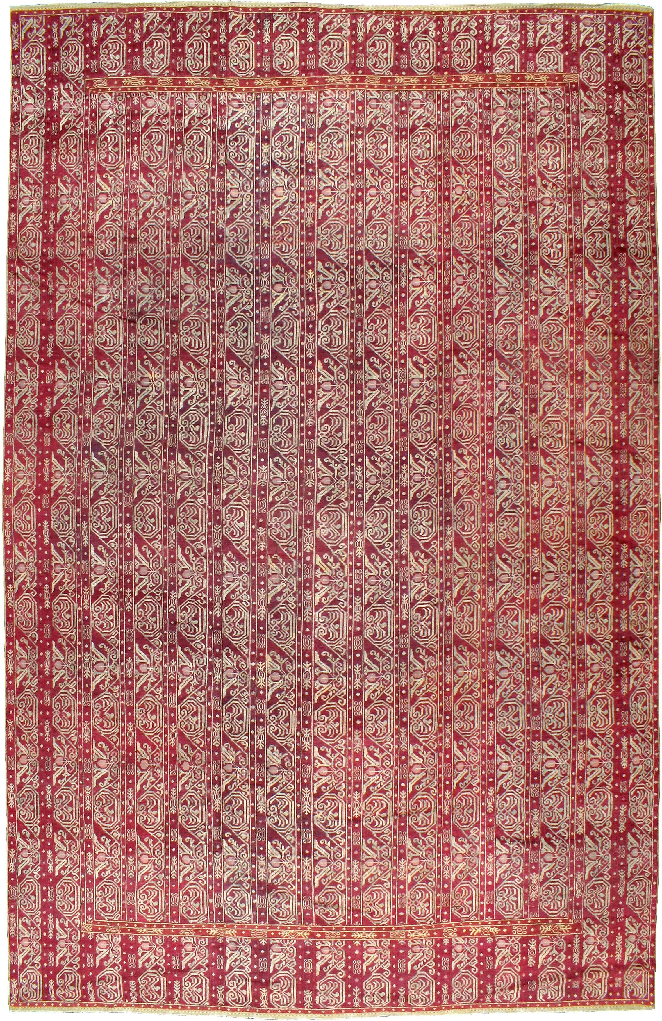 An antique Turkish Ghiordes carpet from the turn of the 20th century with a series of linear vine scrolls known as a cane design sits atop a bright maroon ground.