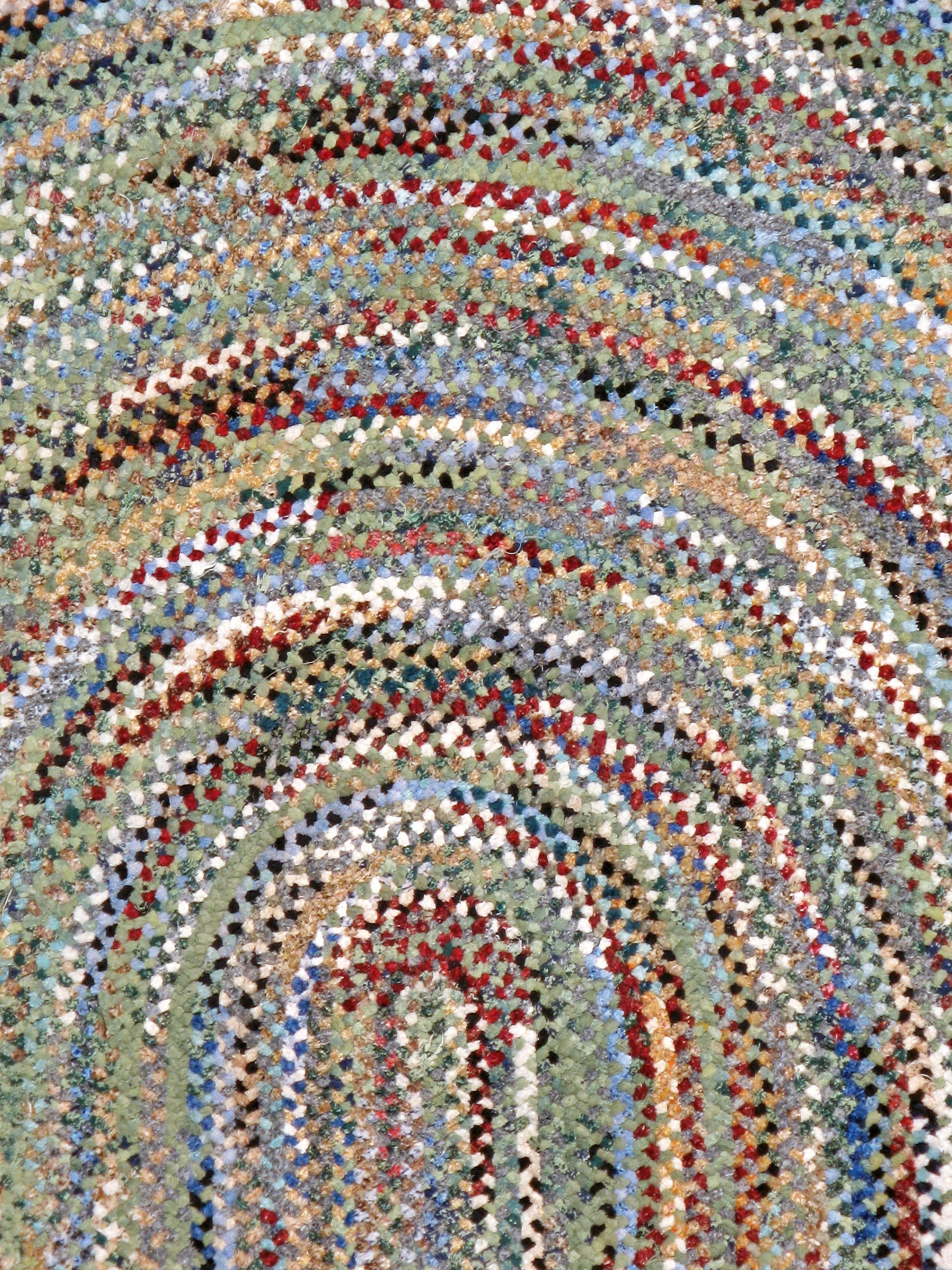 A vintage American Braid carpet from the mid-20th century. This dizzying ‘end-of-day’ braided oval features a virtually uncountable number of fabric bits in an endless color display with black, charcoal, white, grass green, celadon, orange, light
