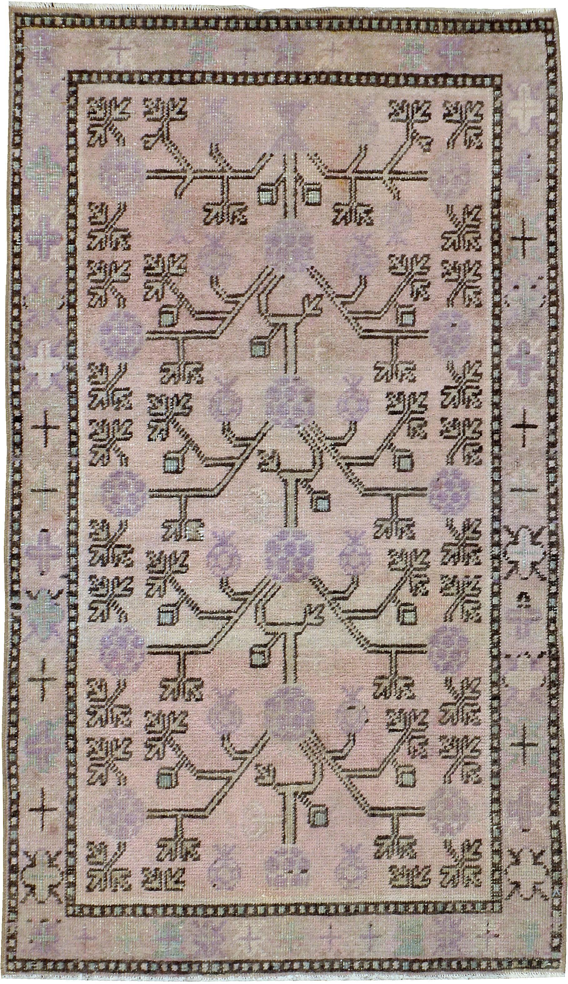 An antique East Turkestan Khotan carpet from the first quarter of the 20th century with a pomegranate design in shades of pink and purple.