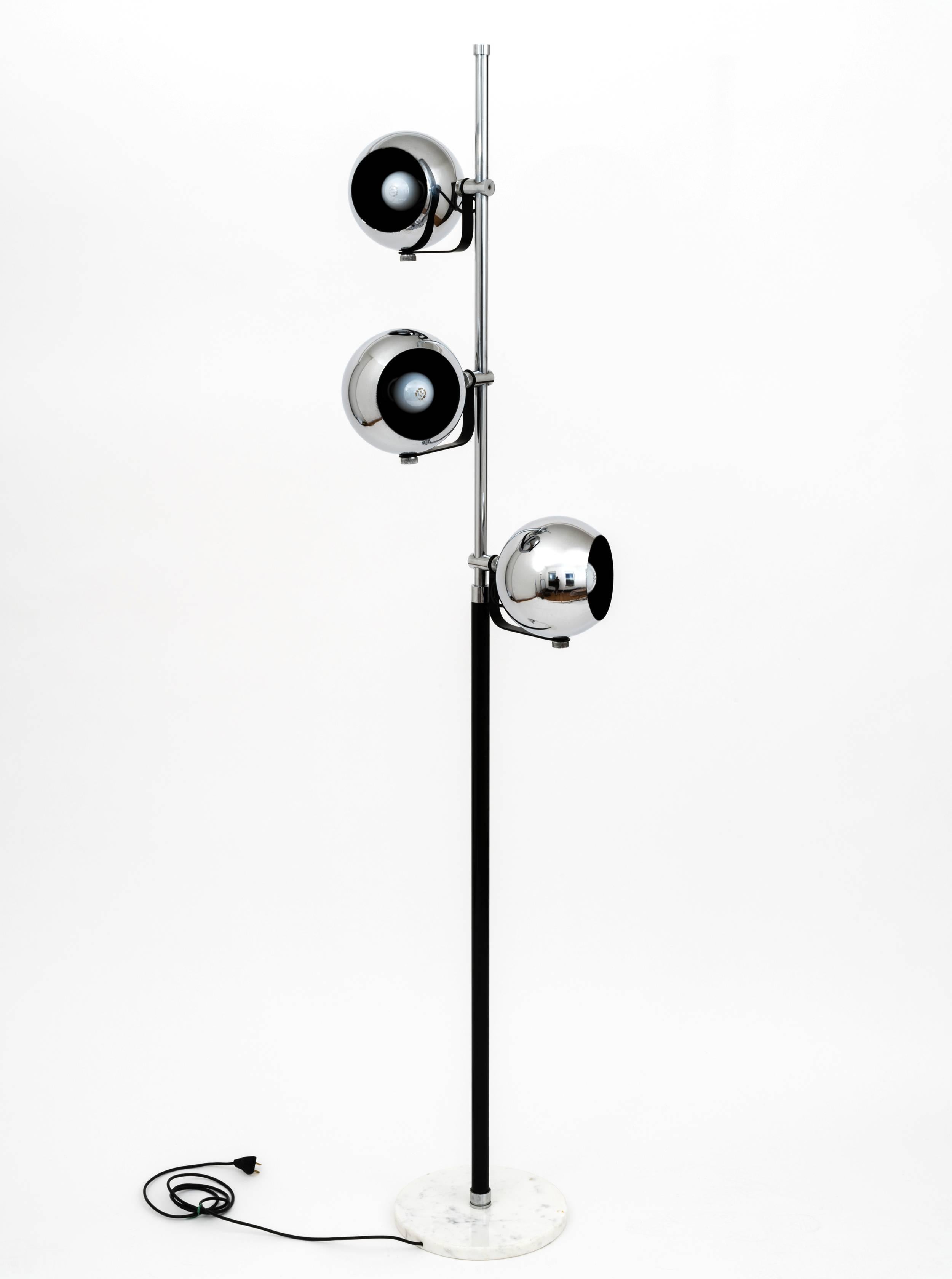 A 1960s floor lamp in the style of Arredoluce comprising a 2-part, tubular center column, the top in chrome and the bottom in black-enameled steel, with 3 chrome lights, each with its own on/off switch and mounted to an L-shaped bracket, all