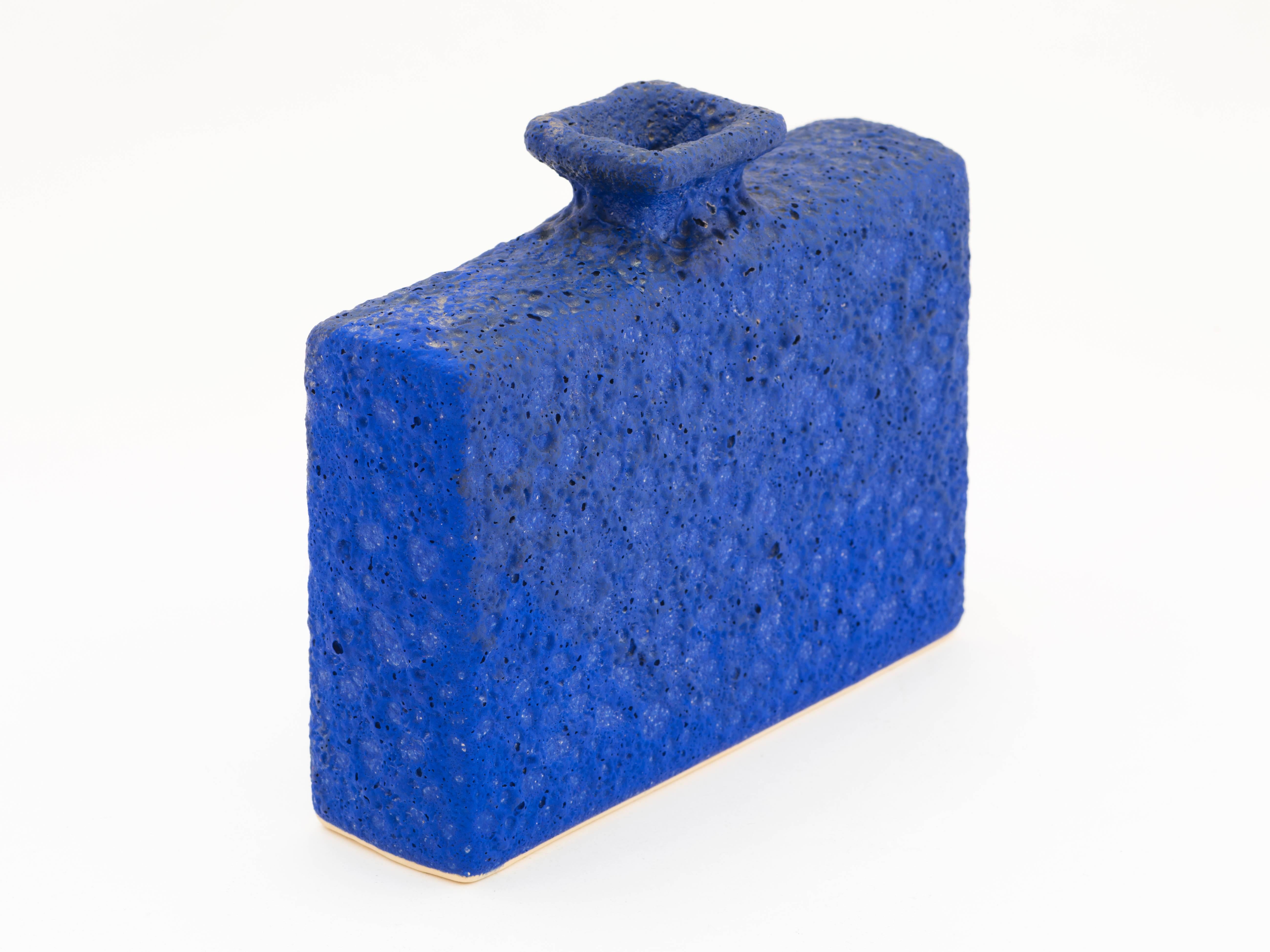 A strikingly simple and heavily glazed ceramic vessel in a slab form with a stout lip produced by Silberdistel, circa 1965. The volcanic glaze is a nearly perfect shade of International Klein Blue and its pockmarked texture over the spare,