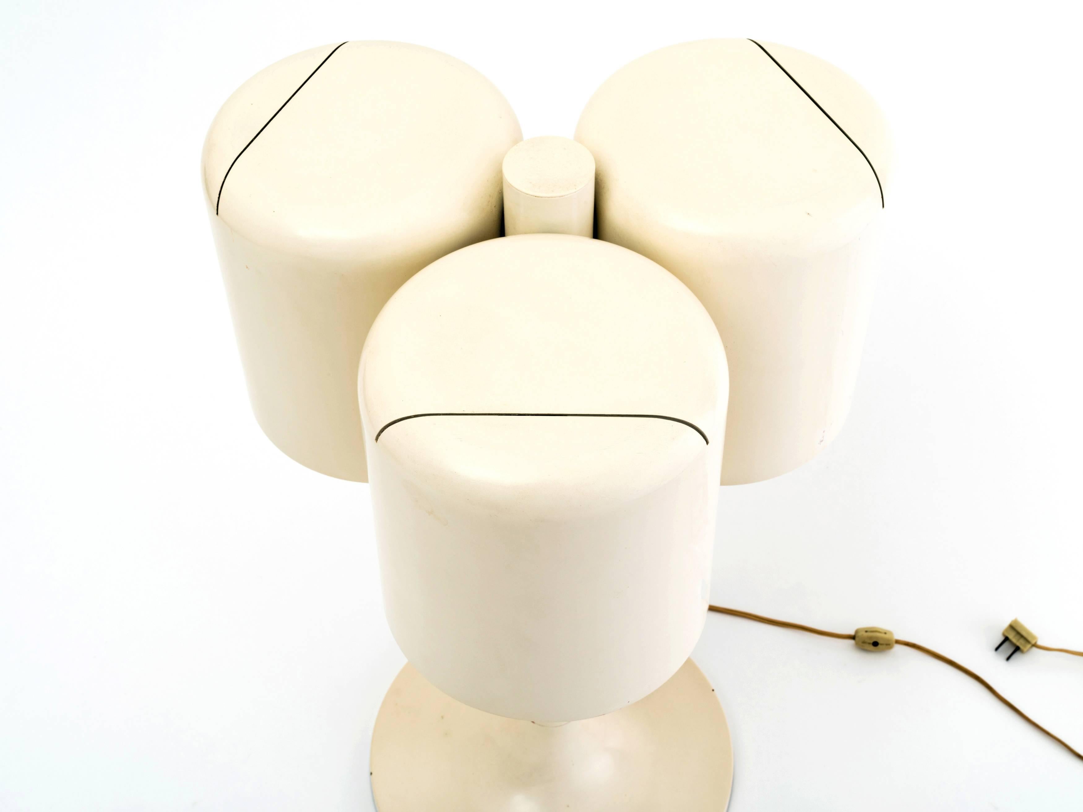 An uncommon table lamp designed by Neal Small in 1971 with a Classic tulip base in steel that supports three cylindrical shades in aluminum, all in an off-white lacquer. Each shade has an off-center slit at top, providing for a subtle uplight glow.