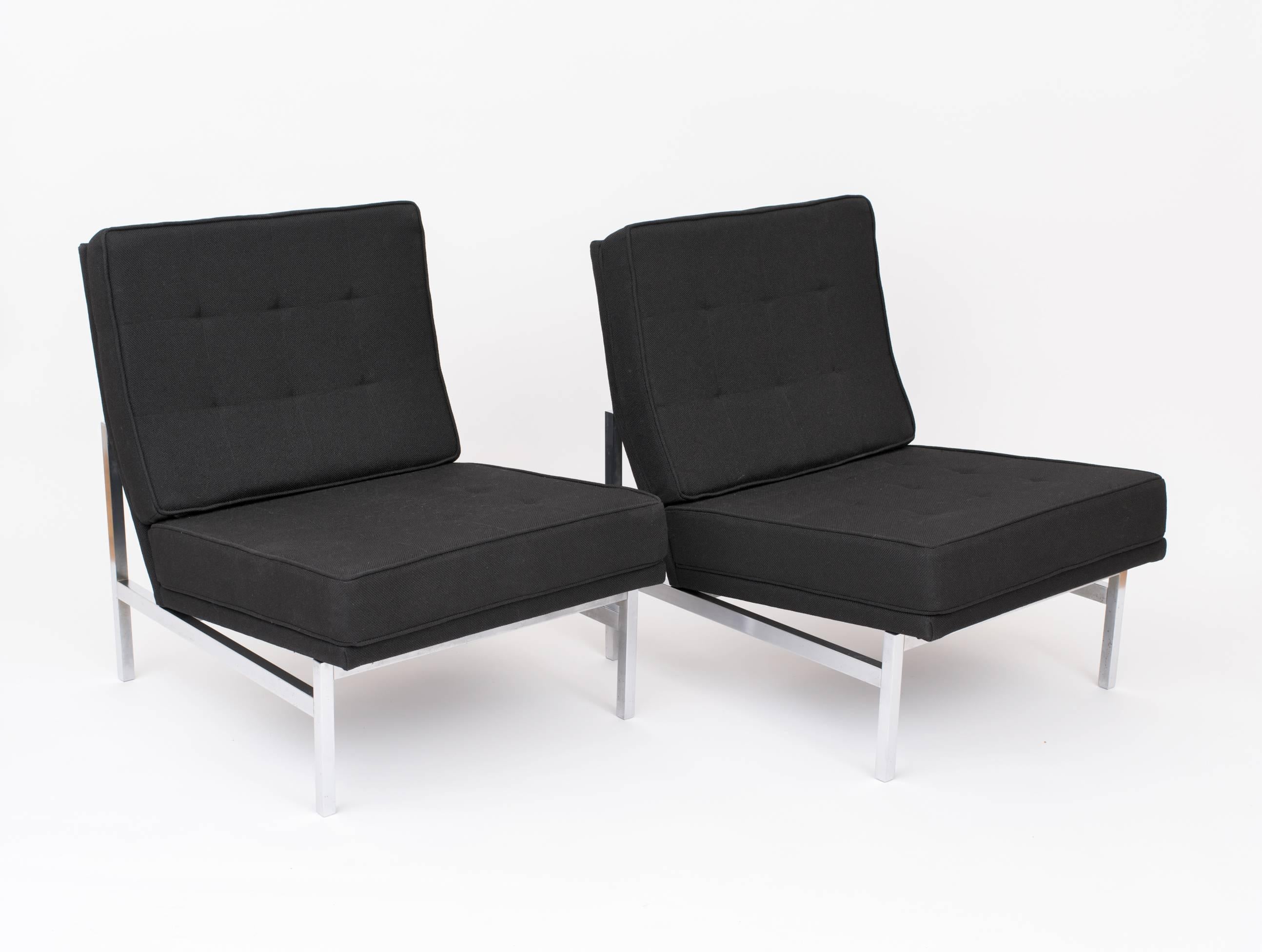 A pair of Florence Knoll model 2551 lounge chairs with square, brushed steel frames that support a pitched, floating seat, featuring brand new, black wool fabric and upholstered as originally designed. We saved the original tags and they are
