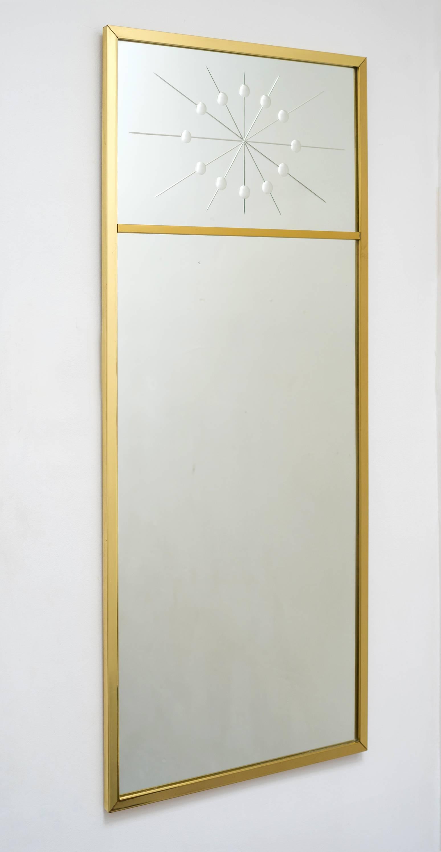 A modern wall mirror in rectangular form comprising a segmented brass frame with the top glass bearing an atomic starburst design motif much in the style of Tommi Parzinger. Perfect as a hall / entryway / console mirror. 