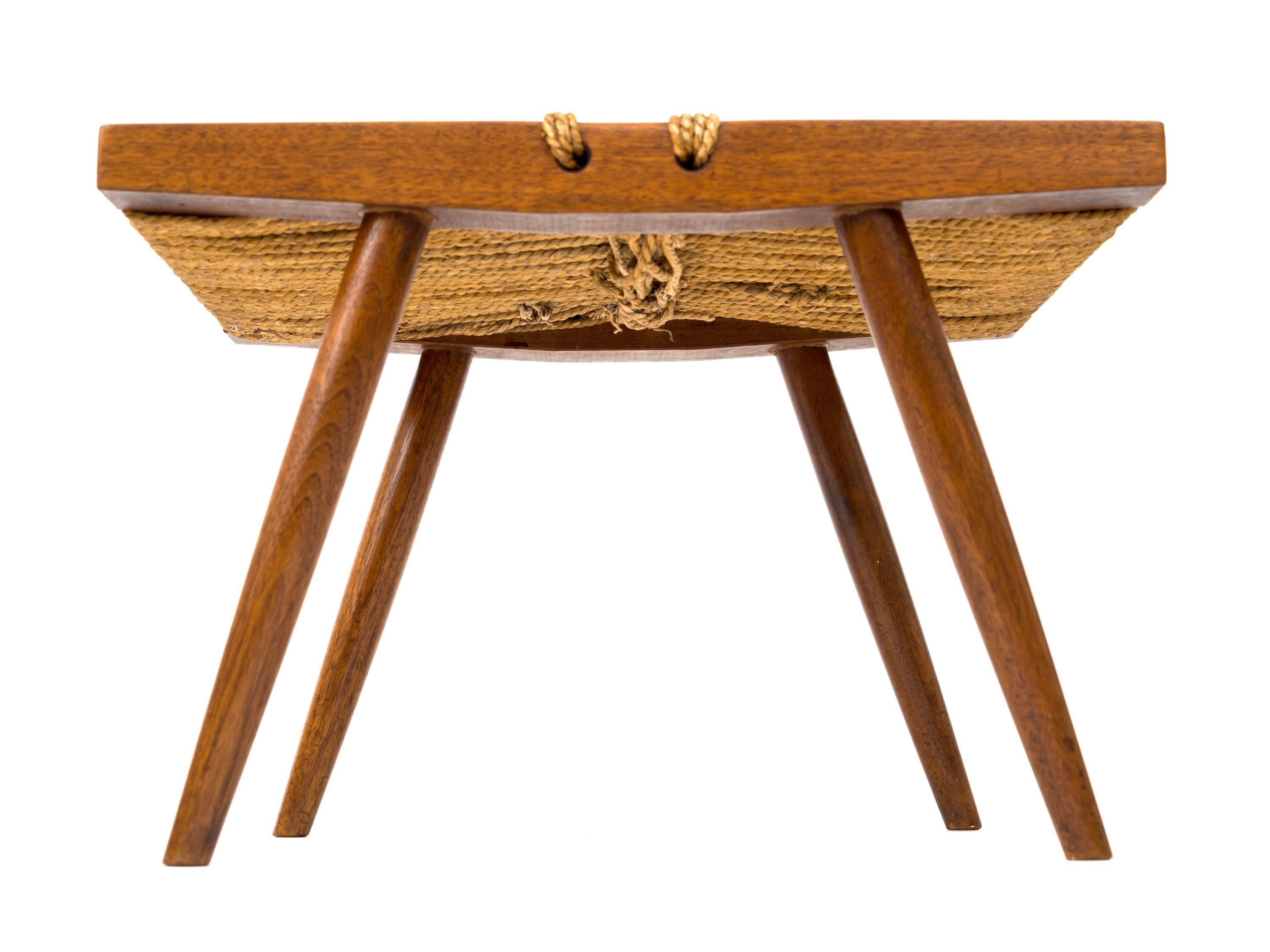 Footstool with splayed legs in walnut and a woven grass rope seat by George Nakashima. This example has a rich patina throughout and dates to the late 50s / early 60s.