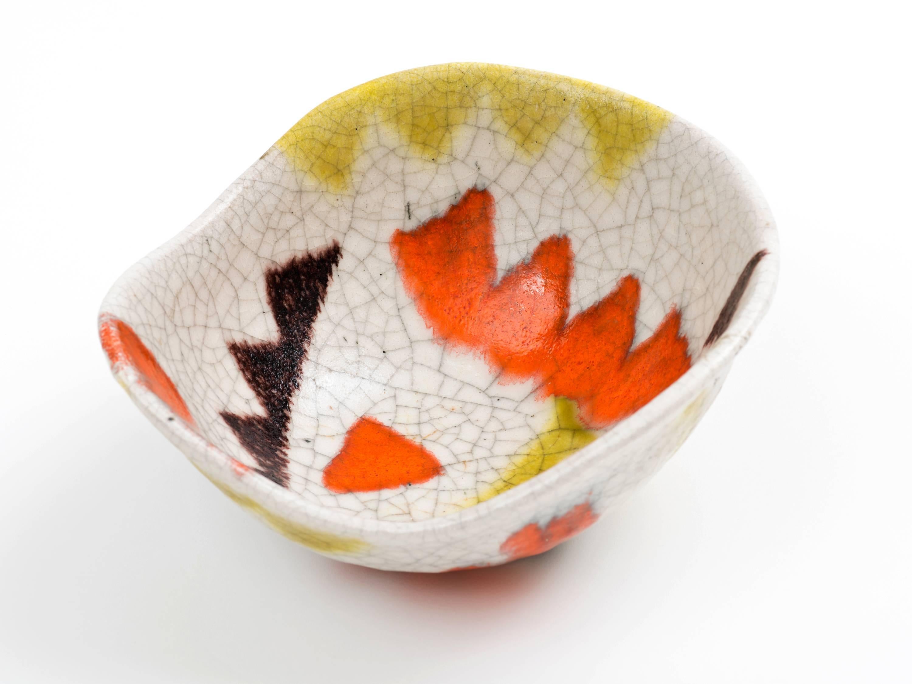 A freeform pottery bowl by Guido Gambone with applied triangular motif decoration in coral, eggplant, and ochre on an ivory ground. Lively tribal design with nice scale - - it's larger than it may appear in these images so please refer to