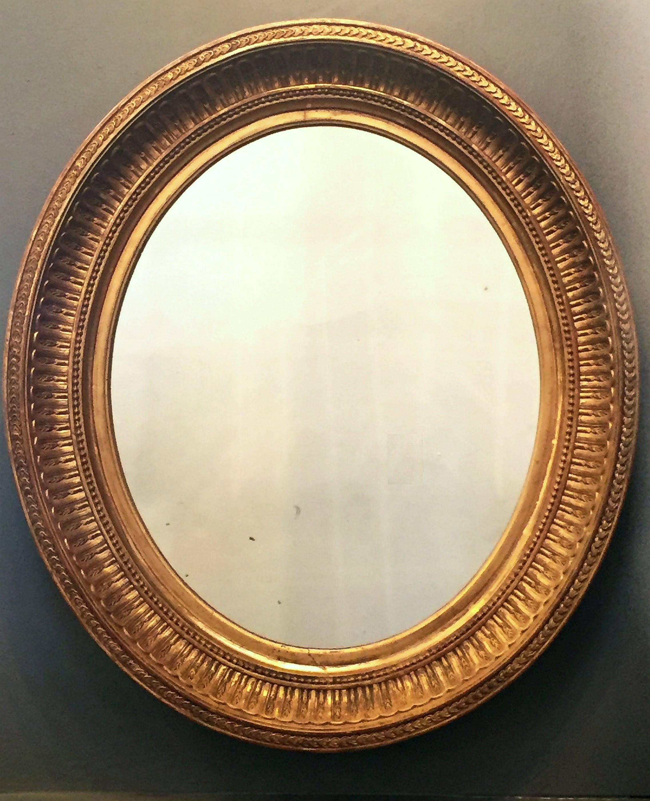 A fine English gilt fame oval mirror in the Classical style, featuring a gilded relief design around the circumference.

Dimensions - 23 3/4