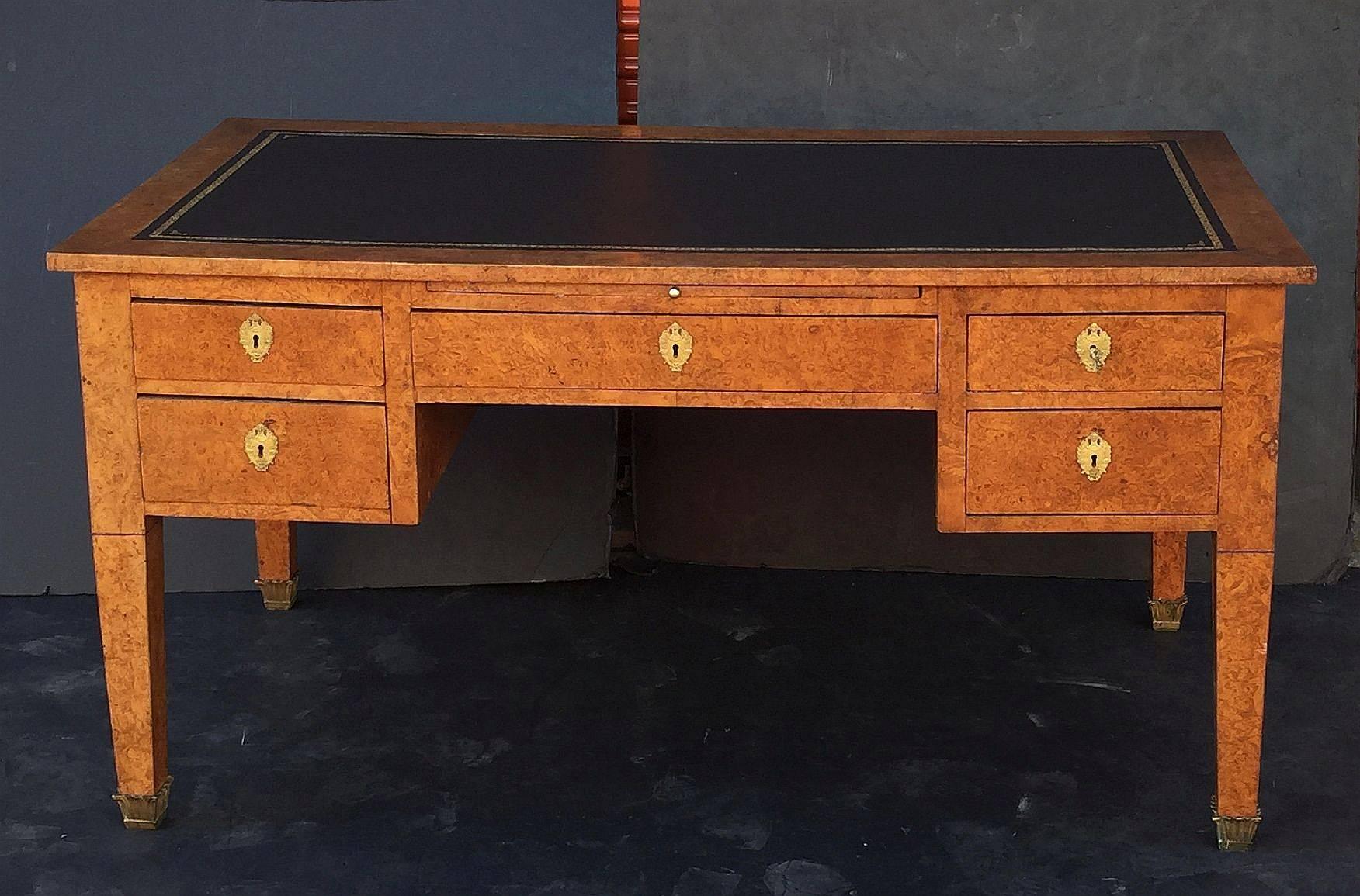 A handsome large Italian desk or writing table, featuring a moulded top of burled wood with inset black leather and embossed gilt edge.
Over a frieze of five working drawers (one large drawer between four small drawers) and working slide (also with