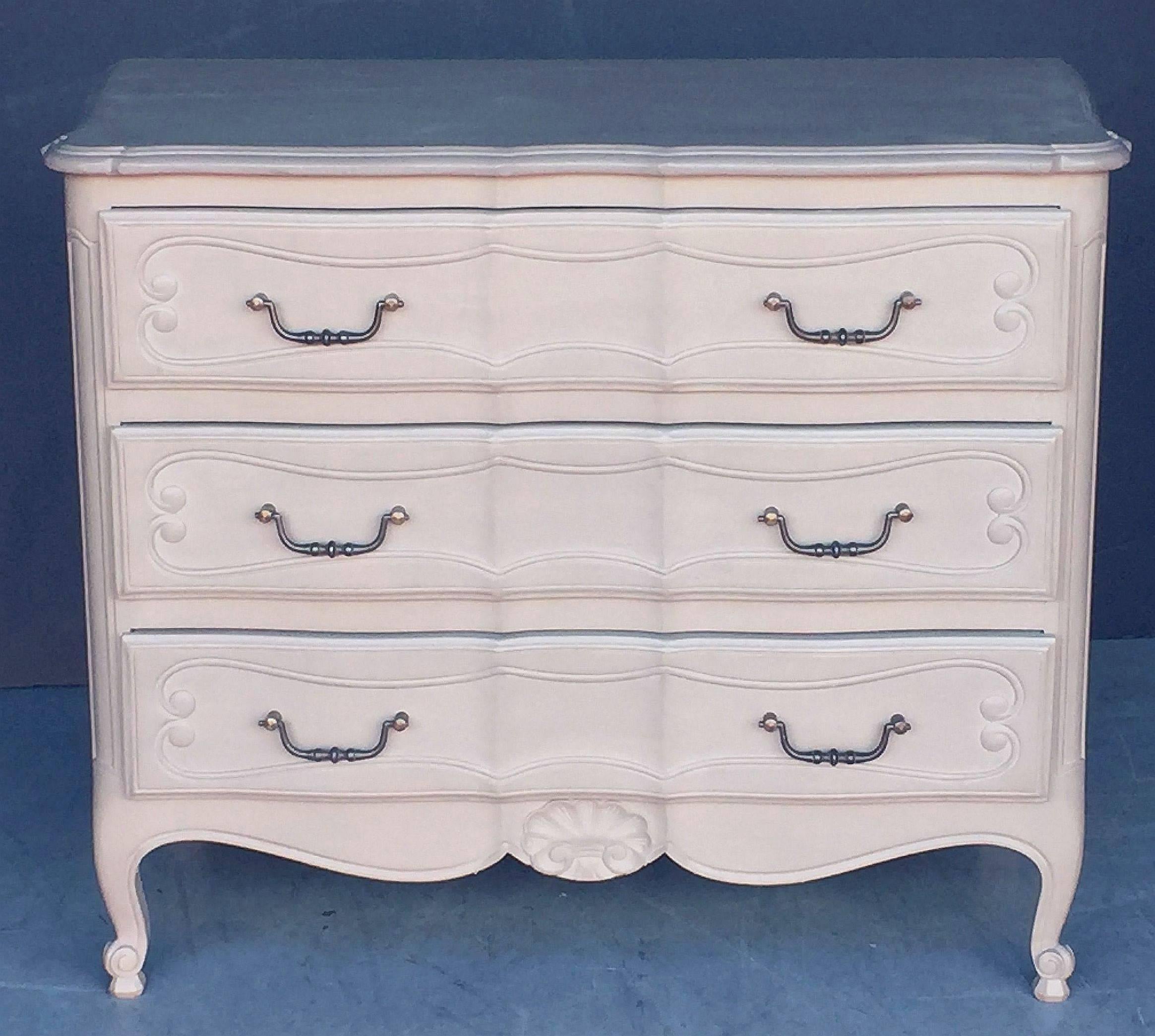 A fine French painted chest of drawers or commode, featuring a moulded top with serpentine edge, over a frieze of three drawers with paneled sides, each drawer with inset scroll design and swan handles, carved shell on the base and resting on facing