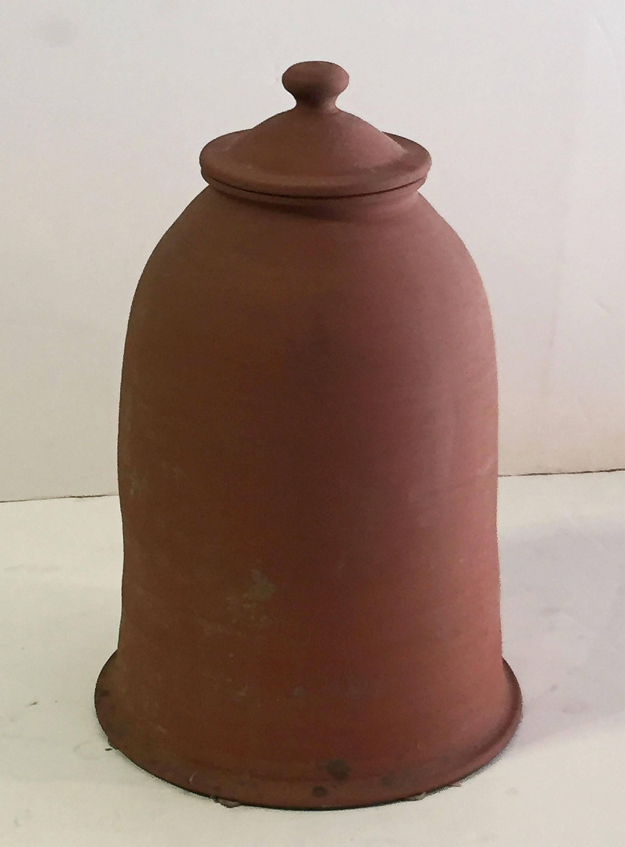 A fine English rhubarb forcer or cloche of terra cotta pottery, for the garden, featuring a bell shape and removable lid.

Rhubarb forcers are bell-shaped pots with a lid covered opening at the top. Used to cover rhubarb to limit photosynthesis,