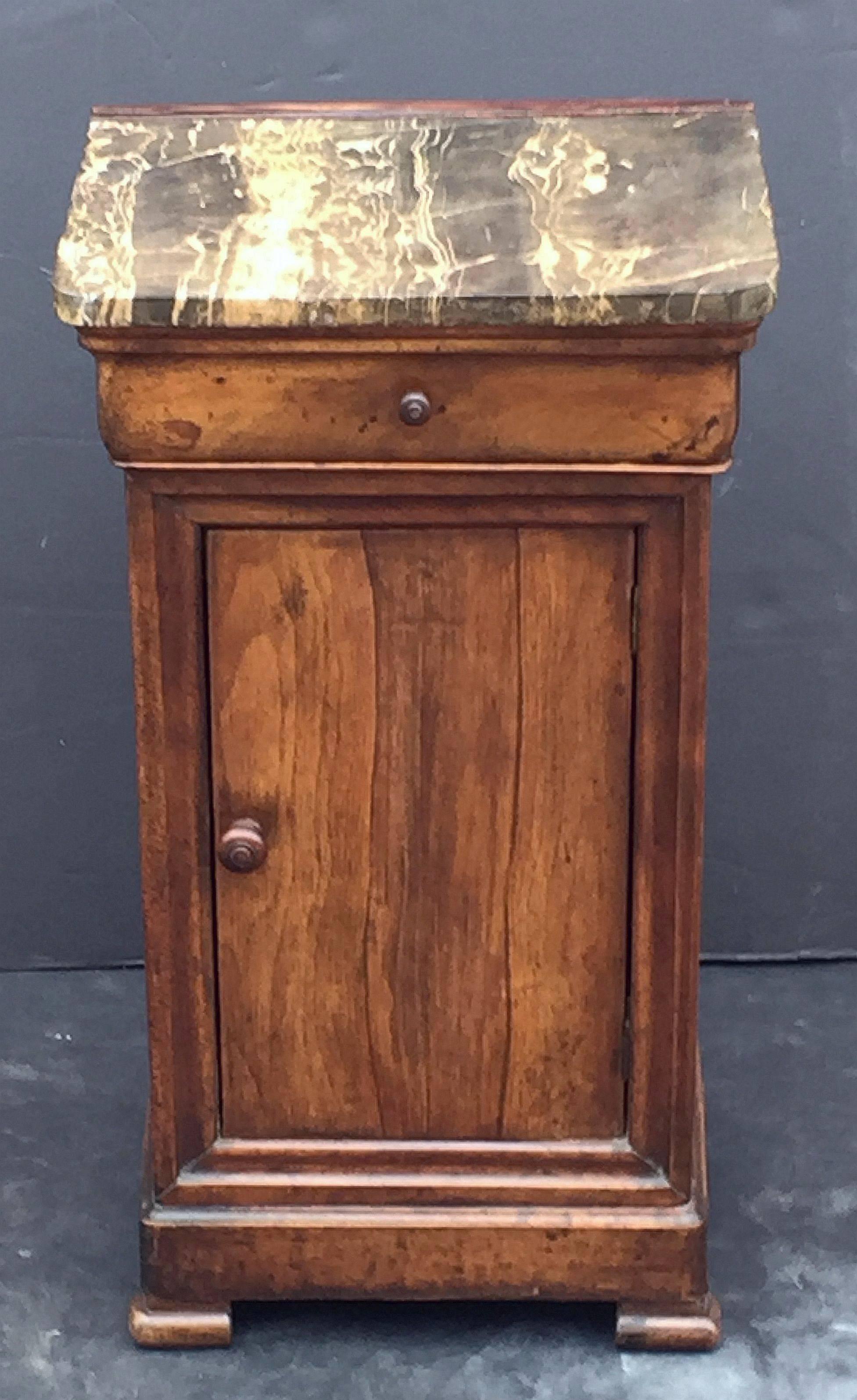 A handsome French nightstand or end table of walnut with figured granite top, with frieze drawer and cabinet door, opening to interior with shelf and resting on moulded plinth and turned feet.