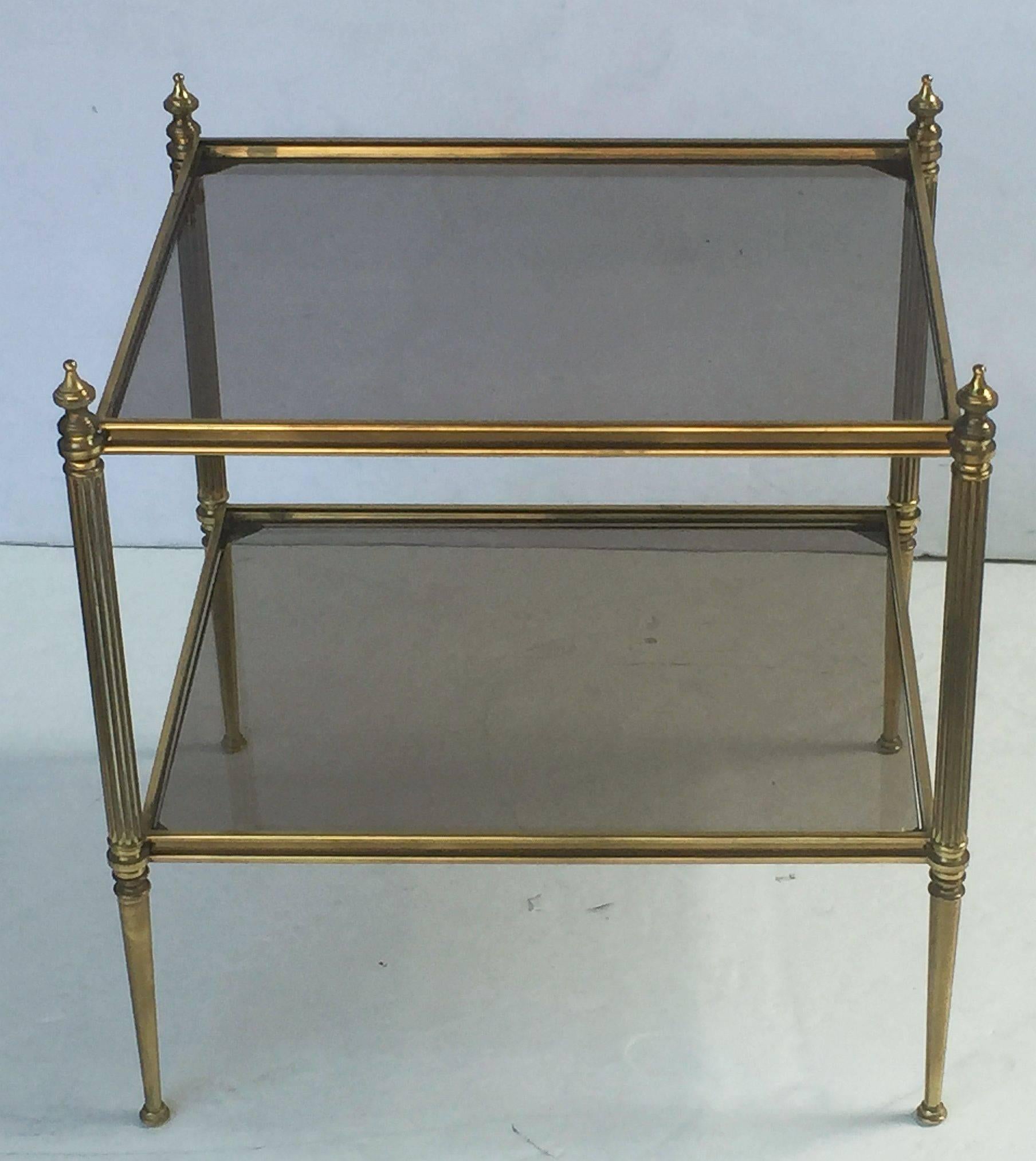 A fine French rectangular coffee or cocktail table, featuring two tiers of smoked glass and a stretcher frame of brass with tapering legs and finials.
